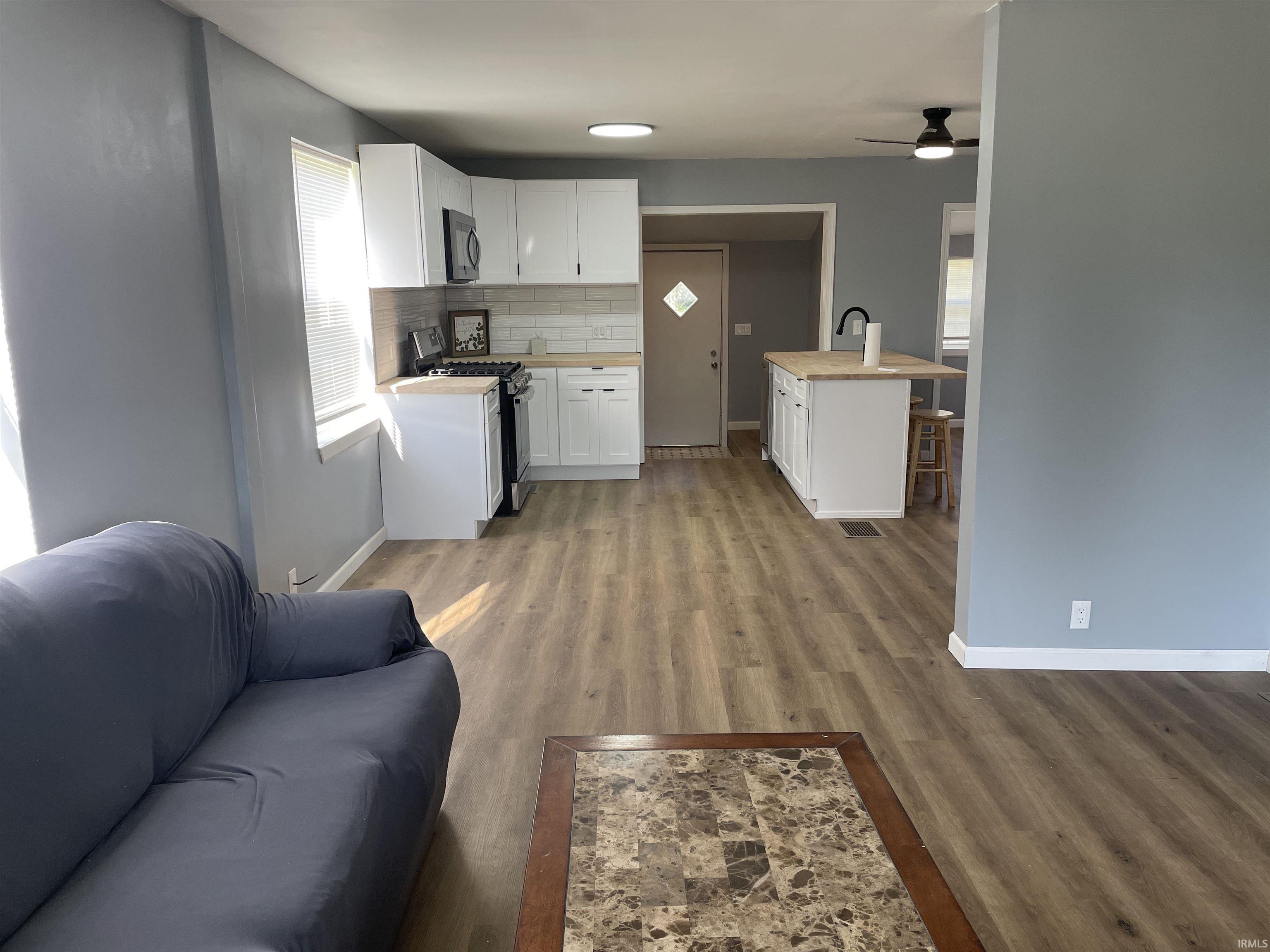 Modern kitchen with white shaker cabinetry, wood-finish flooring, white subway tile backsplash, and a center island with seating
