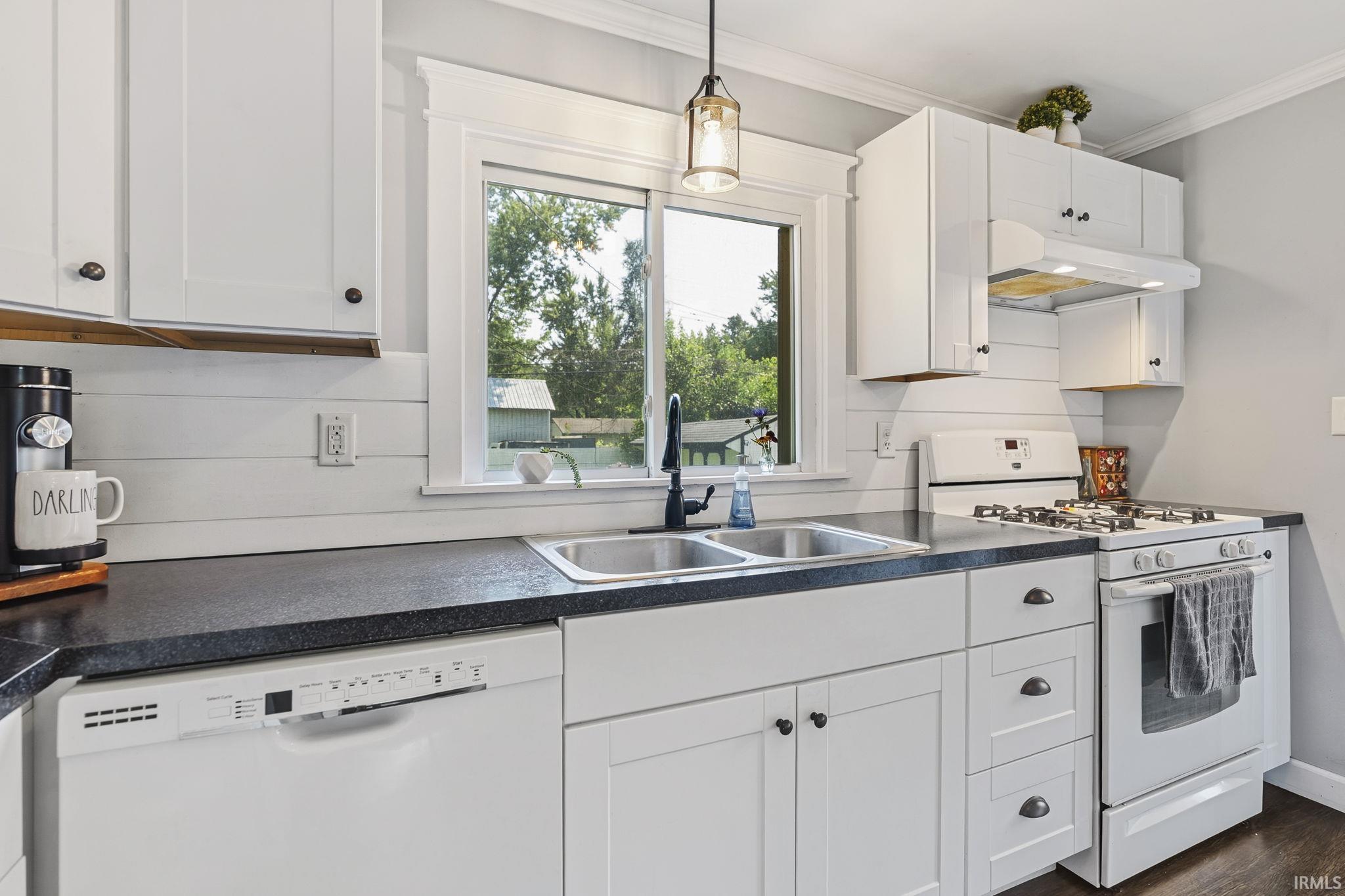 Kitchen featuring white shaker-style cabinetry, dark countertops, and a double basin stainless steel sink
