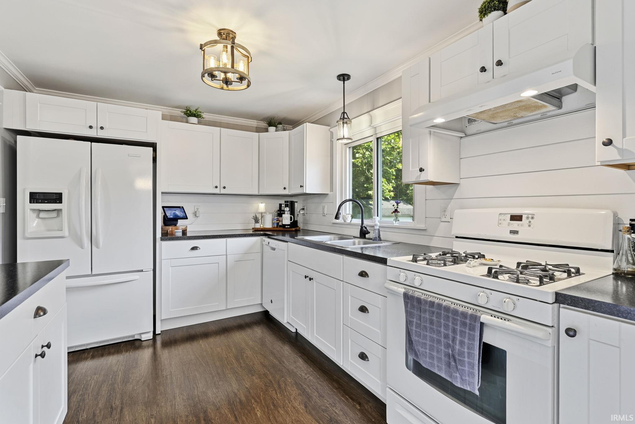 Kitchen featuring white shaker cabinetry, dark countertops, wood-finish flooring, a stainless steel sink with a gooseneck faucet, and a gas range