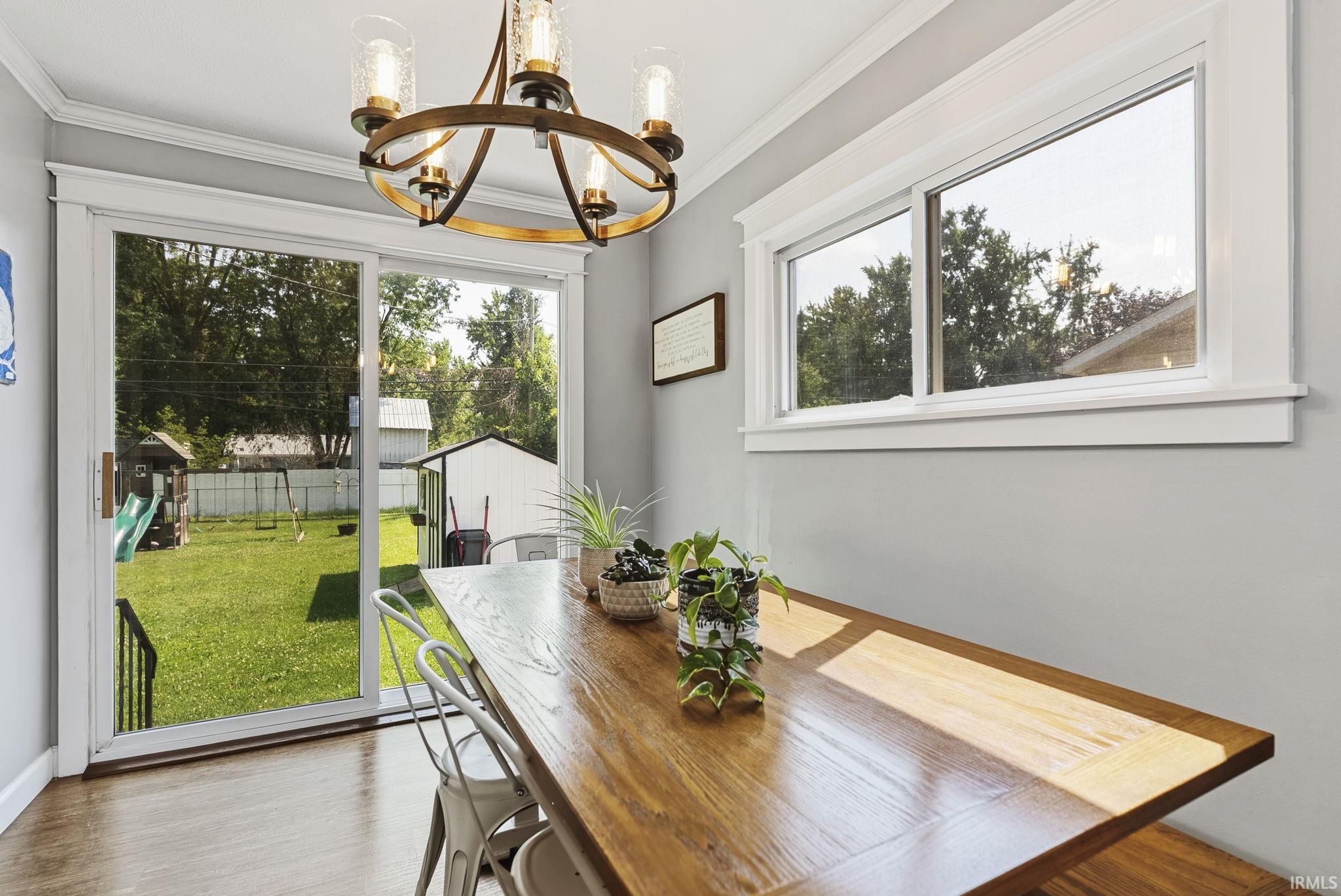Dining area featuring wood-finish flooring, light gray walls, and white crown molding