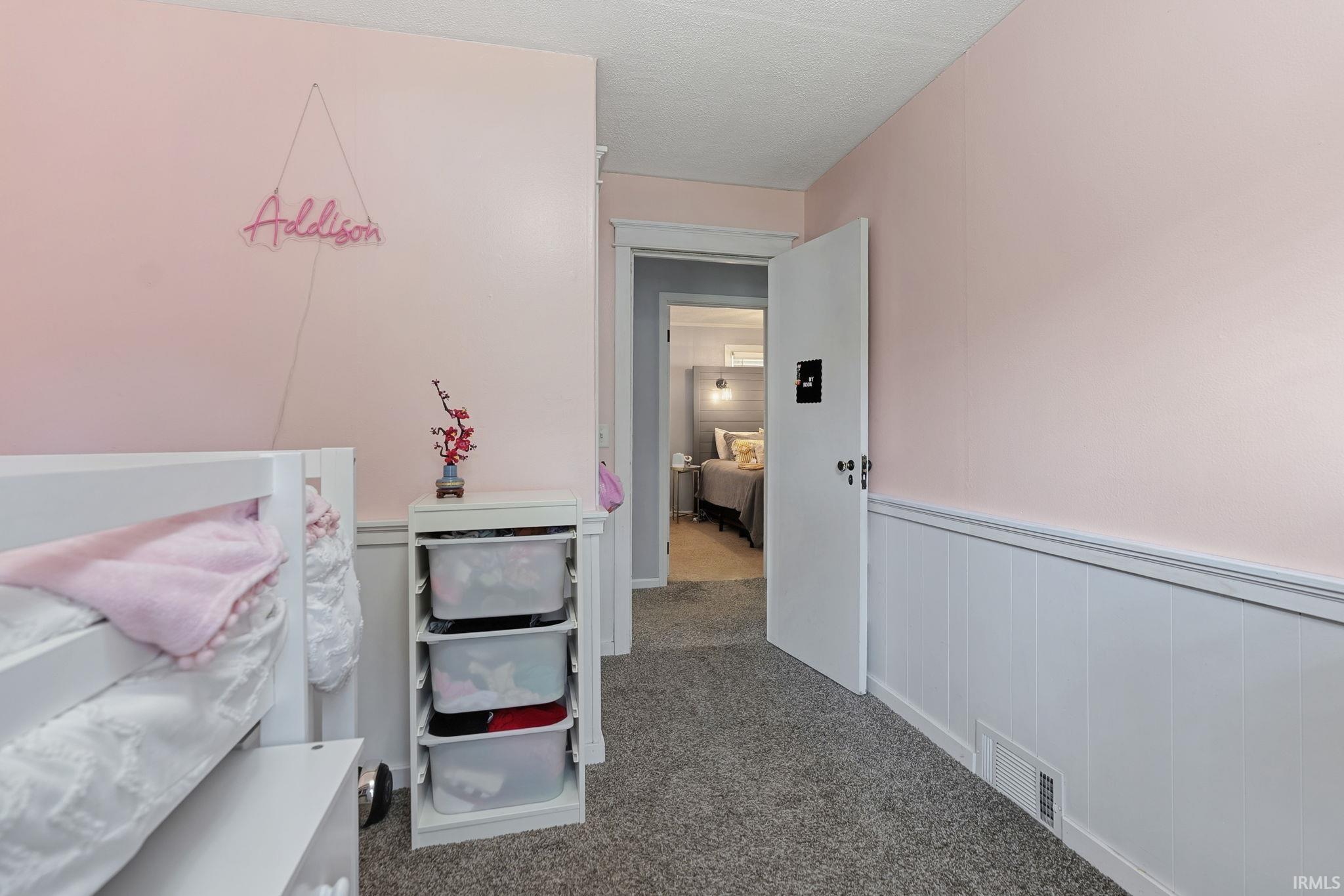 Interior room with plush gray carpet flooring, white wainscoting, and light pink walls