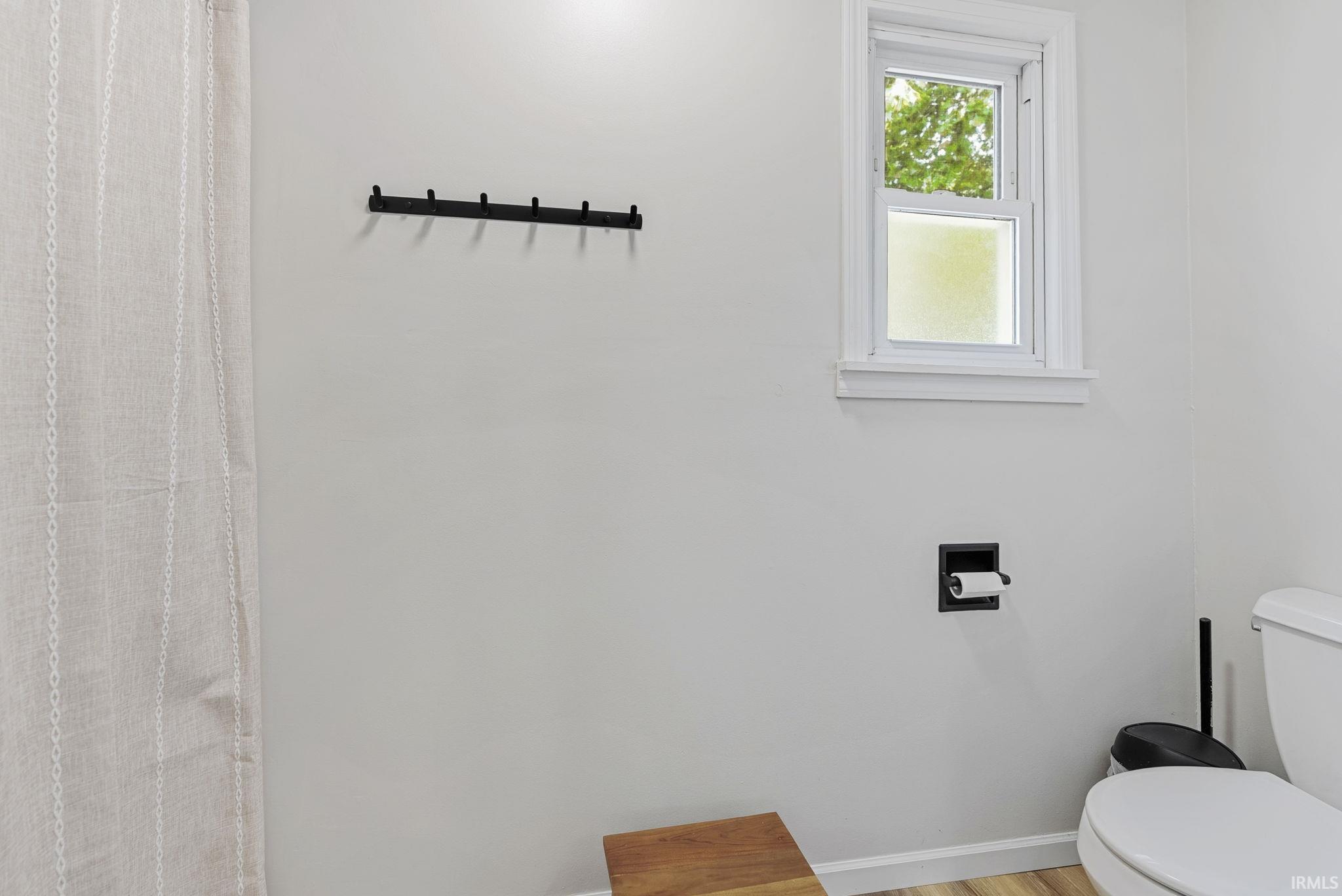 White-framed window above a recessed toilet paper holder