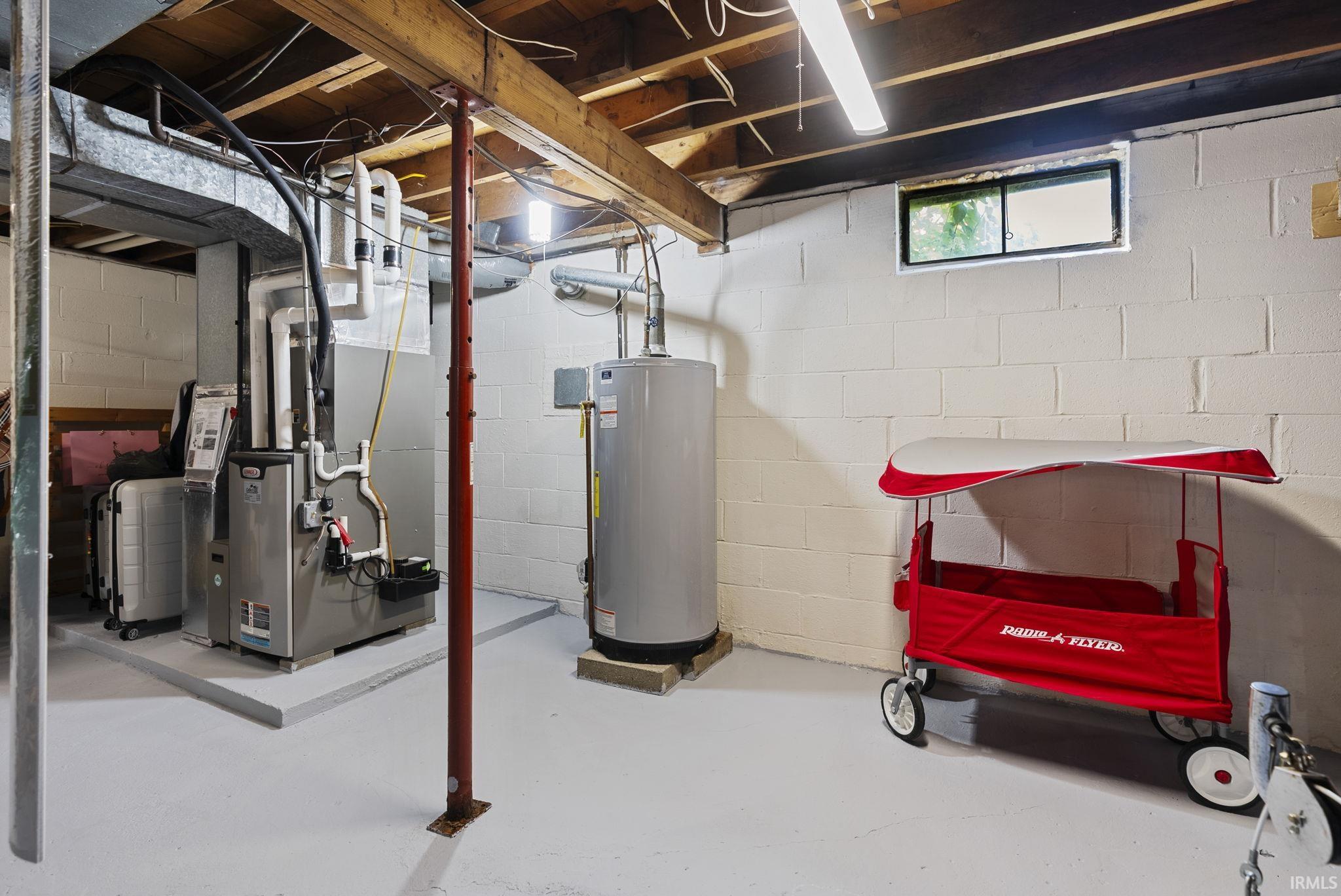 Utility area featuring a furnace system, water heater, and painted concrete block walls