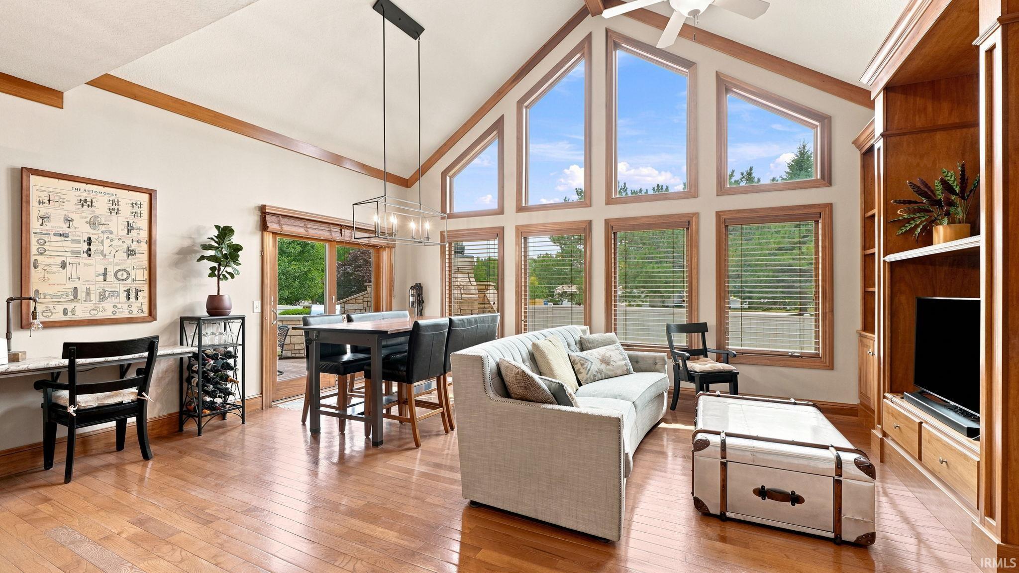 Vaulted ceiling living area featuring wood-finish flooring, a wall of windows, built-in entertainment cabinetry, and a glass sliding door