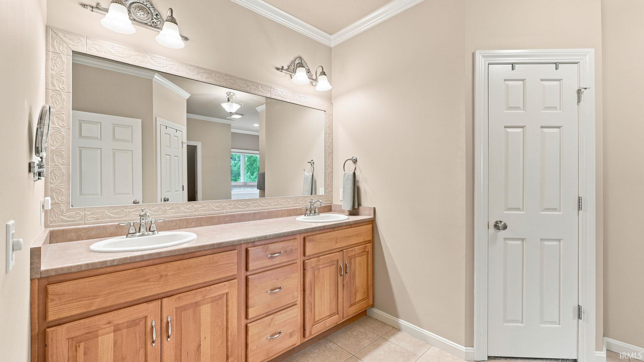 Double vanity with light wood cabinetry, dual undermount sinks, and a laminate countertop