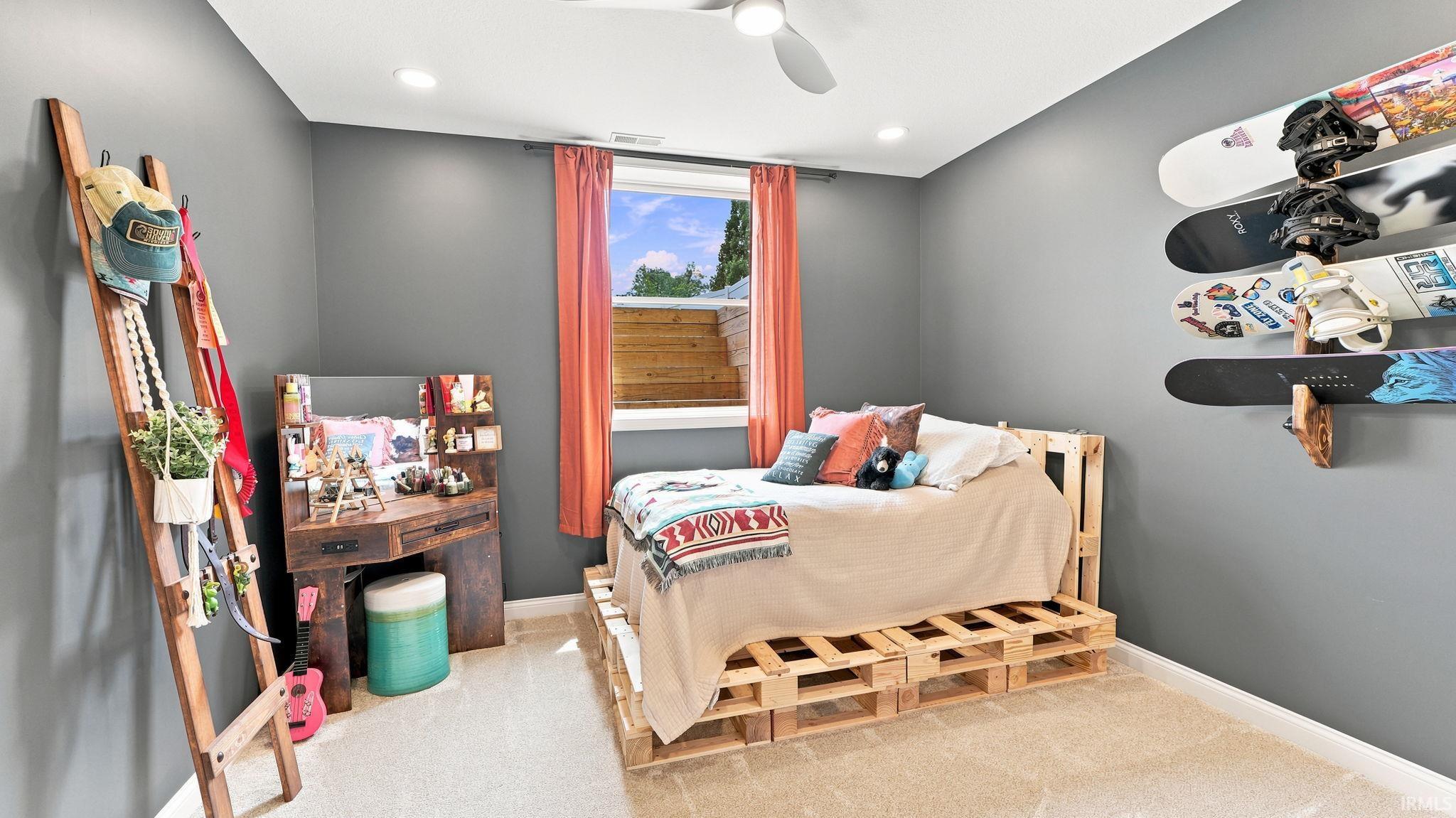 Bedroom featuring light-toned carpeting, a window with red drapery, and recessed lighting