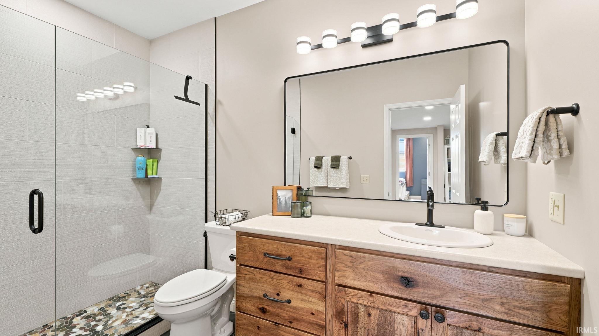 Bathroom featuring a rustic wood vanity with a white countertop, an oval undermount sink, and matte black fixtures