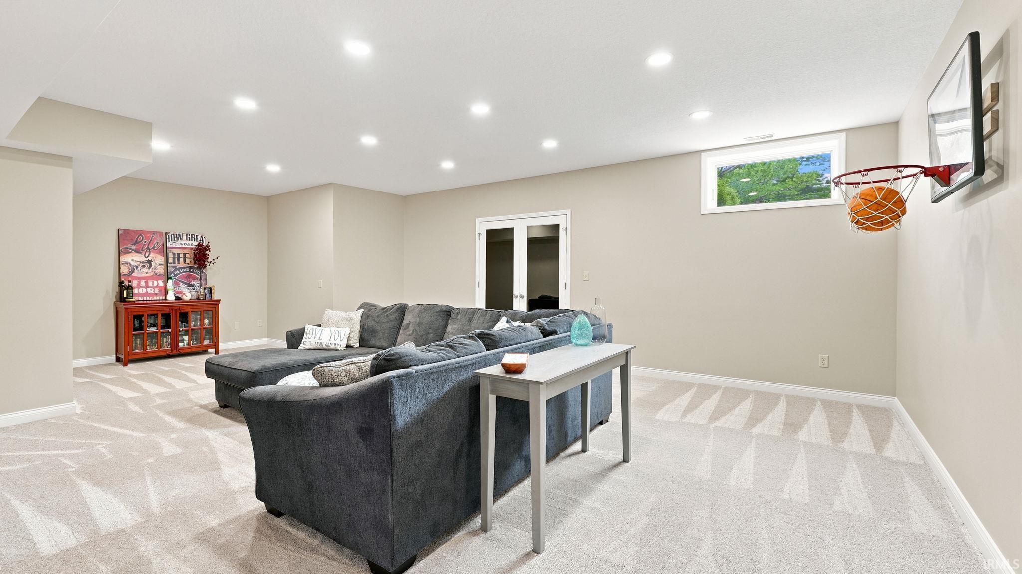 Spacious lower-level room featuring light-toned carpeting and recessed ceiling lights