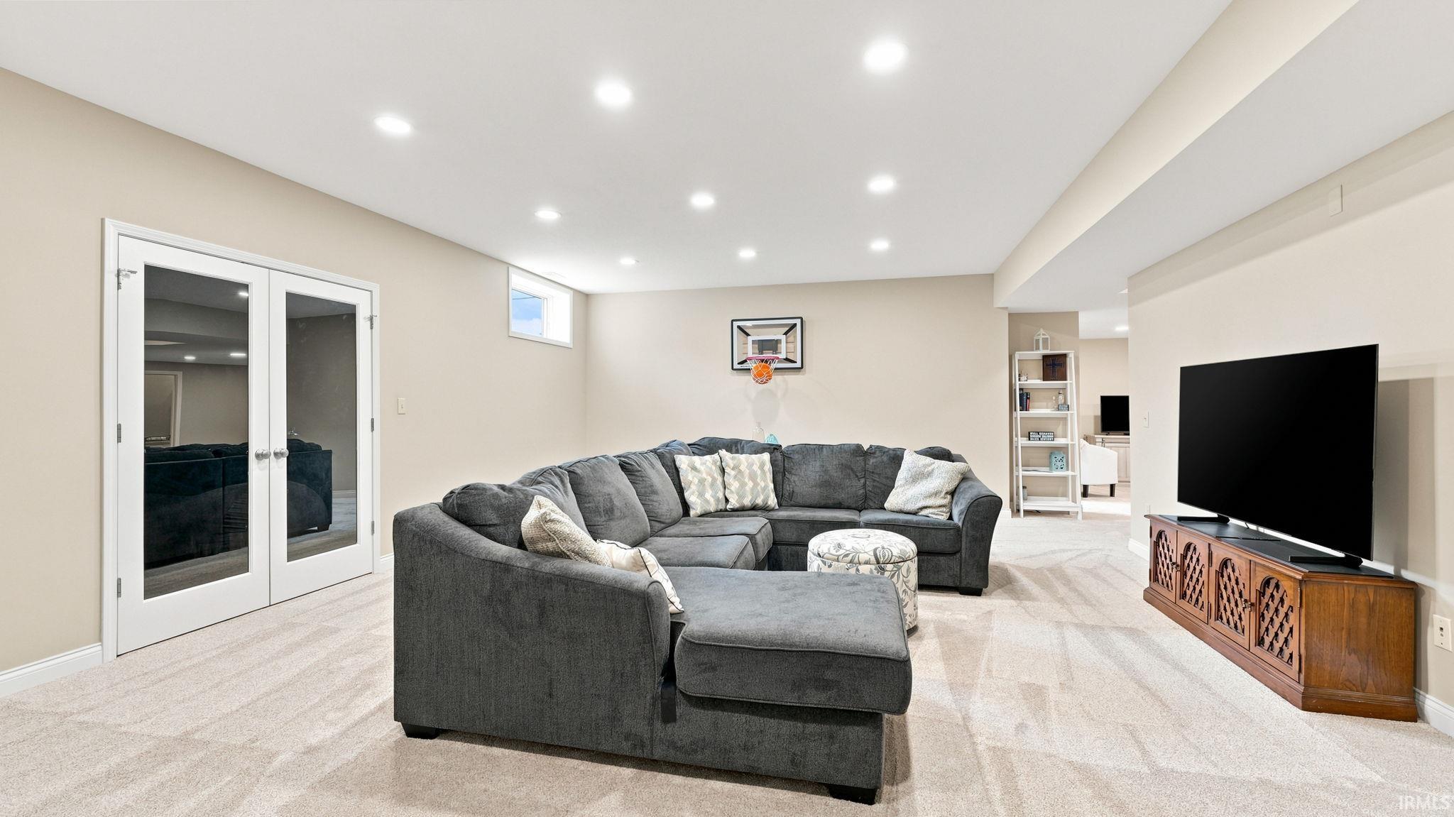 Spacious finished room featuring recessed lighting, light-toned carpet flooring, egress window, and white trim