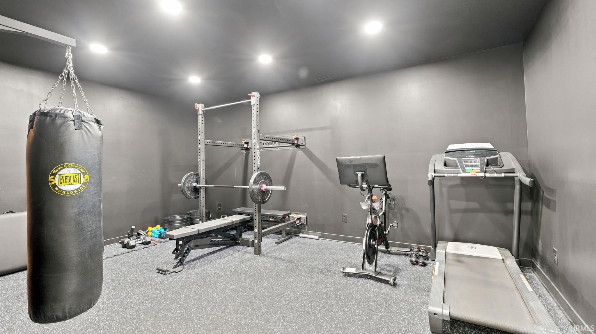 Dedicated fitness space featuring recessed lighting, durable gray wall finishes, and specialized rubber flooring