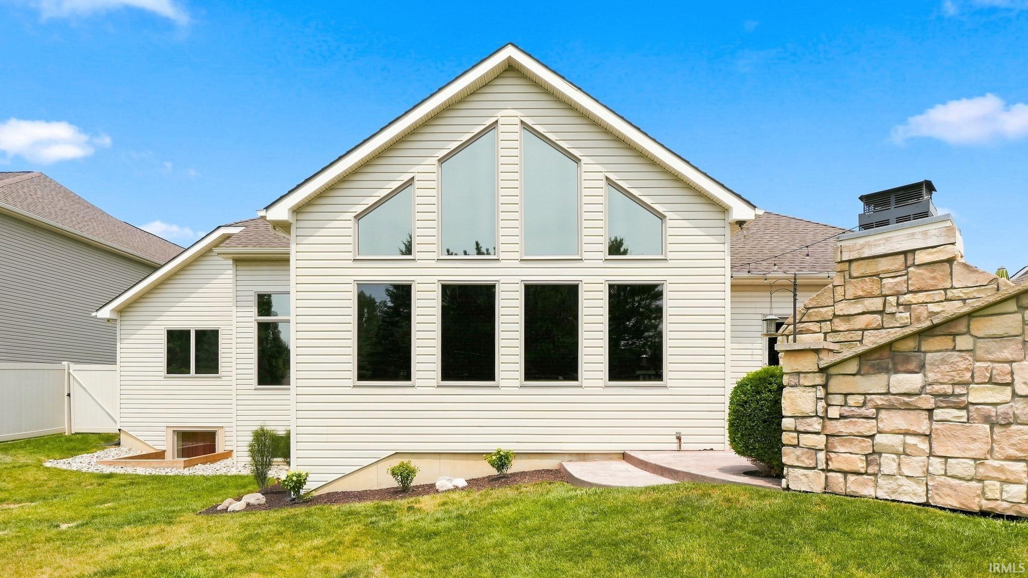 Rear exterior featuring a gable roofline, multiple geometric windows, and light-colored siding