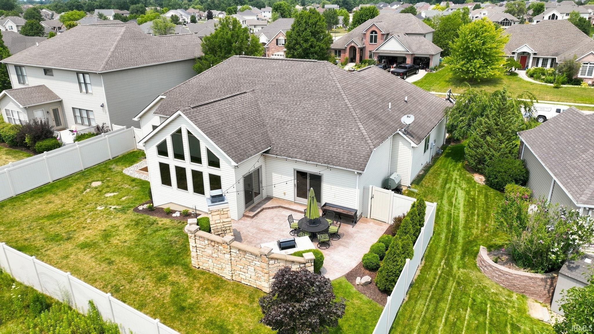 Rear exterior featuring a stone paver patio with a built-in stone half-wall, a stucco exterior, and a white privacy fence