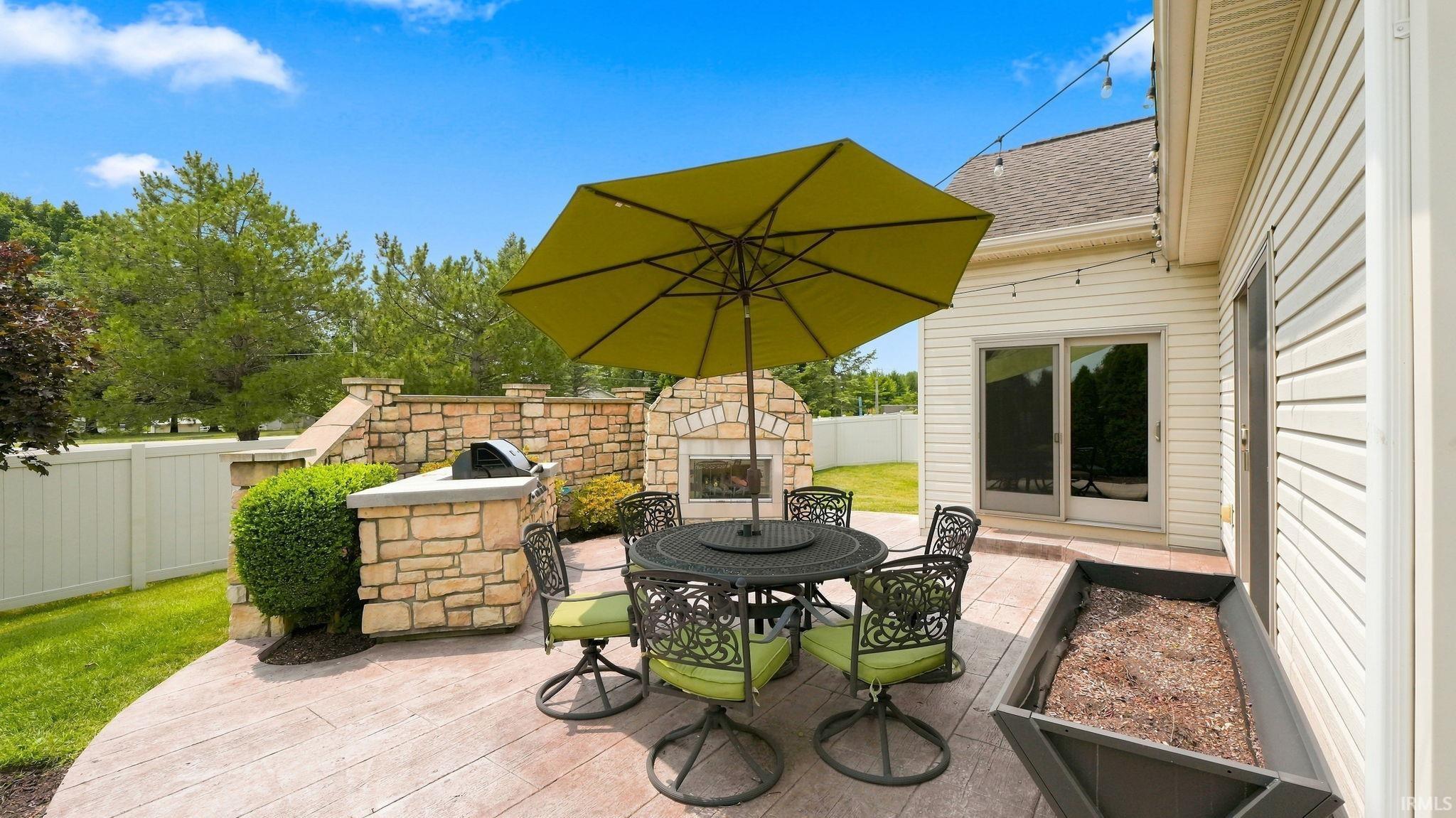 Outdoor patio featuring stamped concrete, a built-in stone grill station, a stone fireplace, and sliding glass door access to the interior