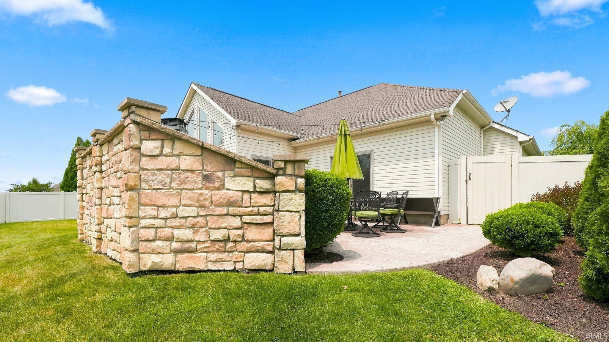 Exterior stone wall and an arched patio featuring a beige paver surface