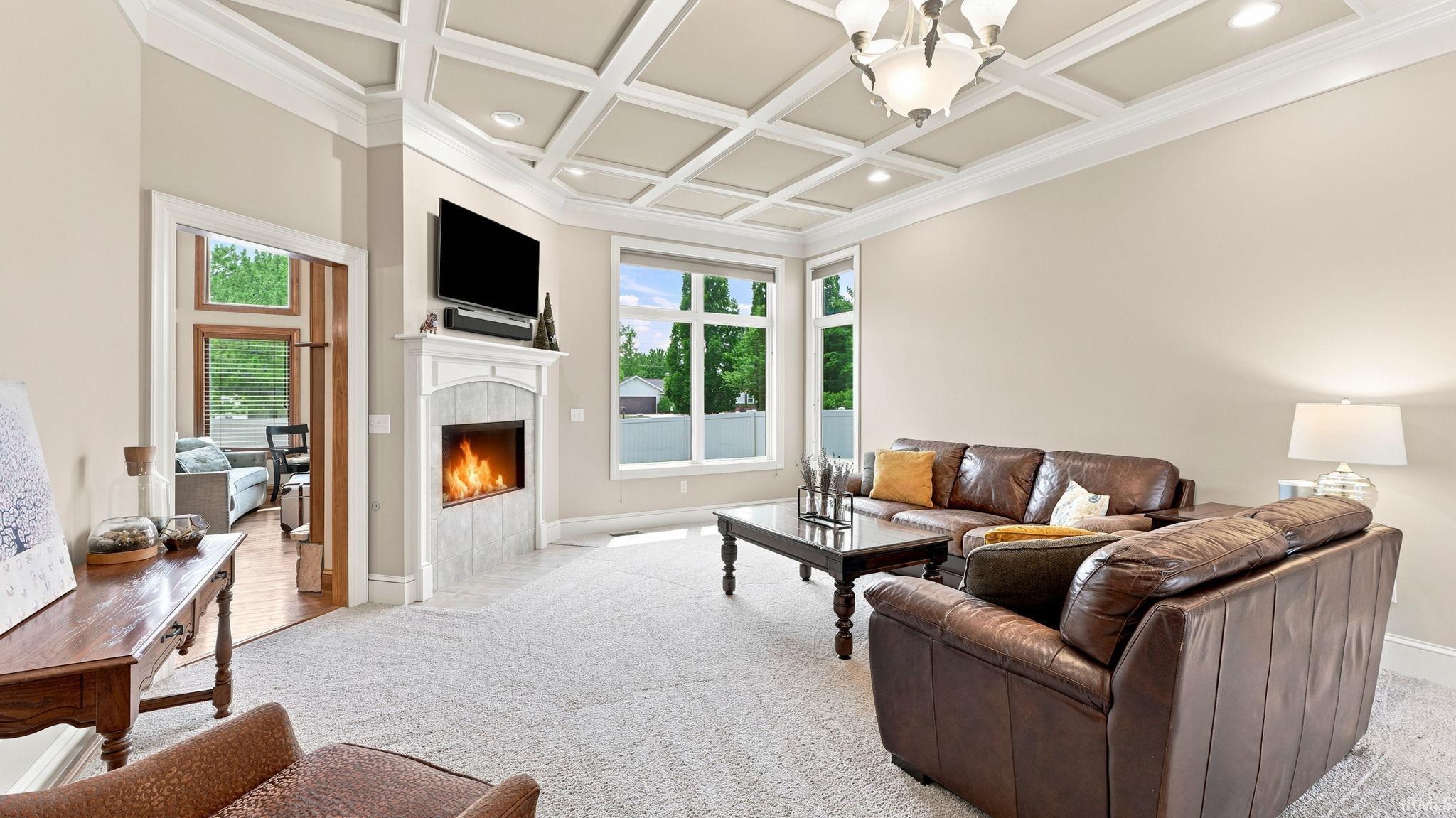 Living area featuring a coffered ceiling with recessed lighting and a central chandelier