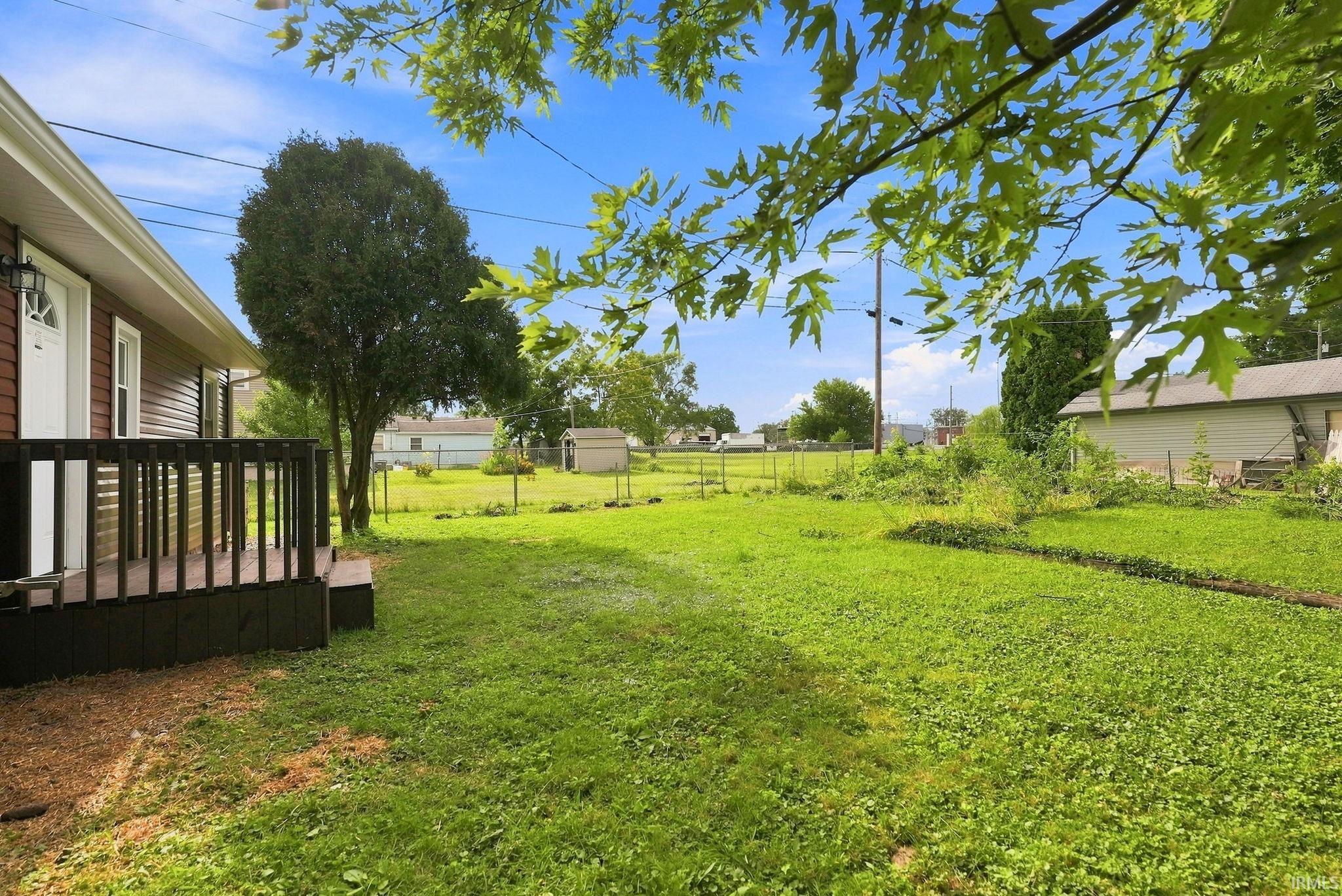 Expansive grassy yard area with mature trees and a fenced perimeter