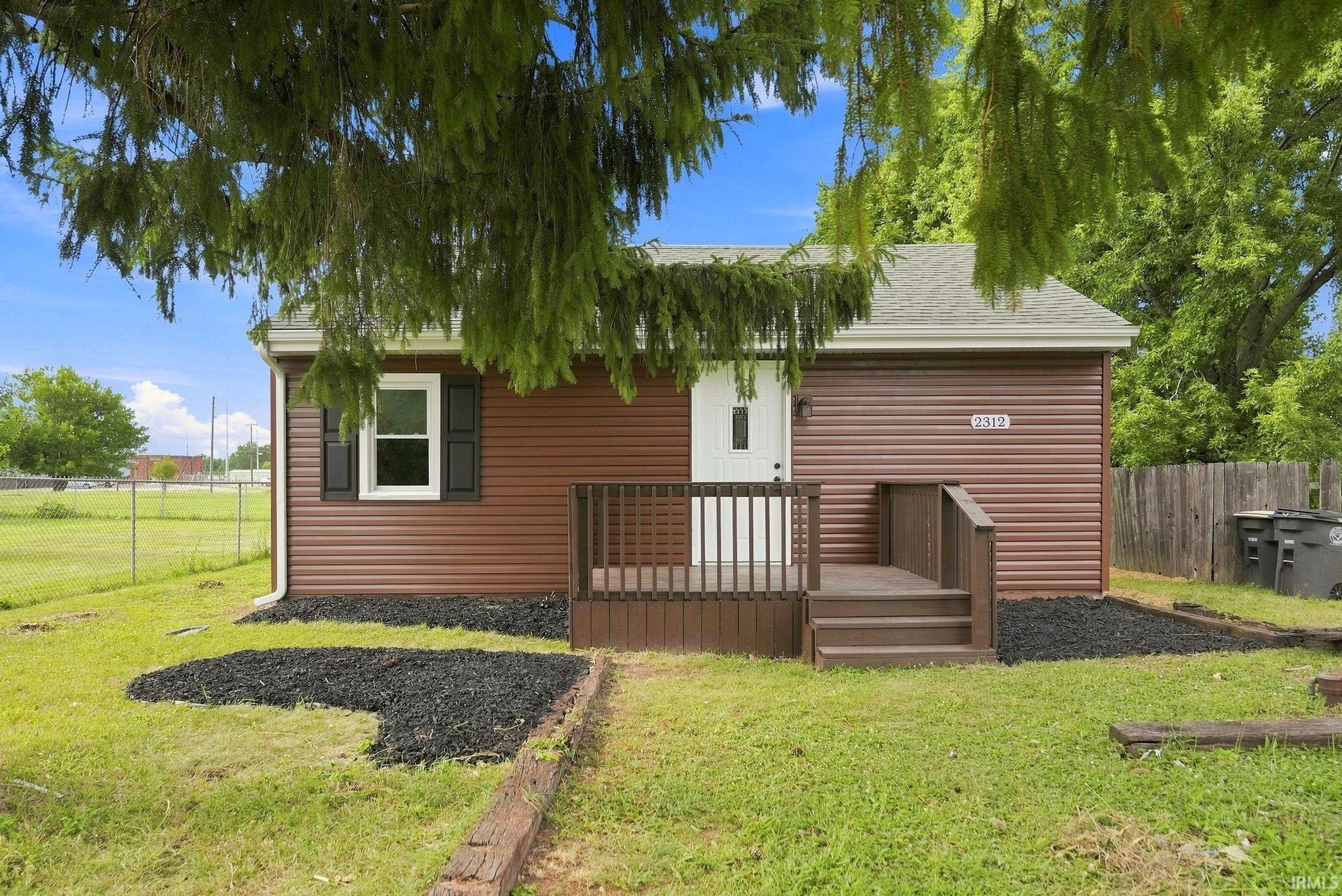 Brown horizontal siding exterior with a white entry door and dark wood porch