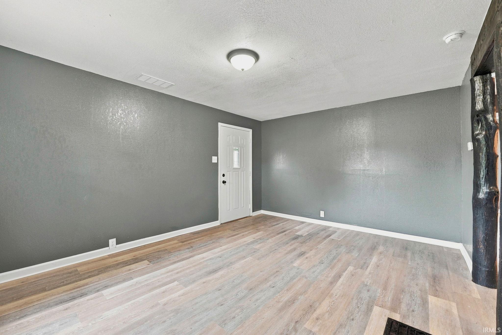 Spacious room featuring wood-finish flooring and a neutral color palette