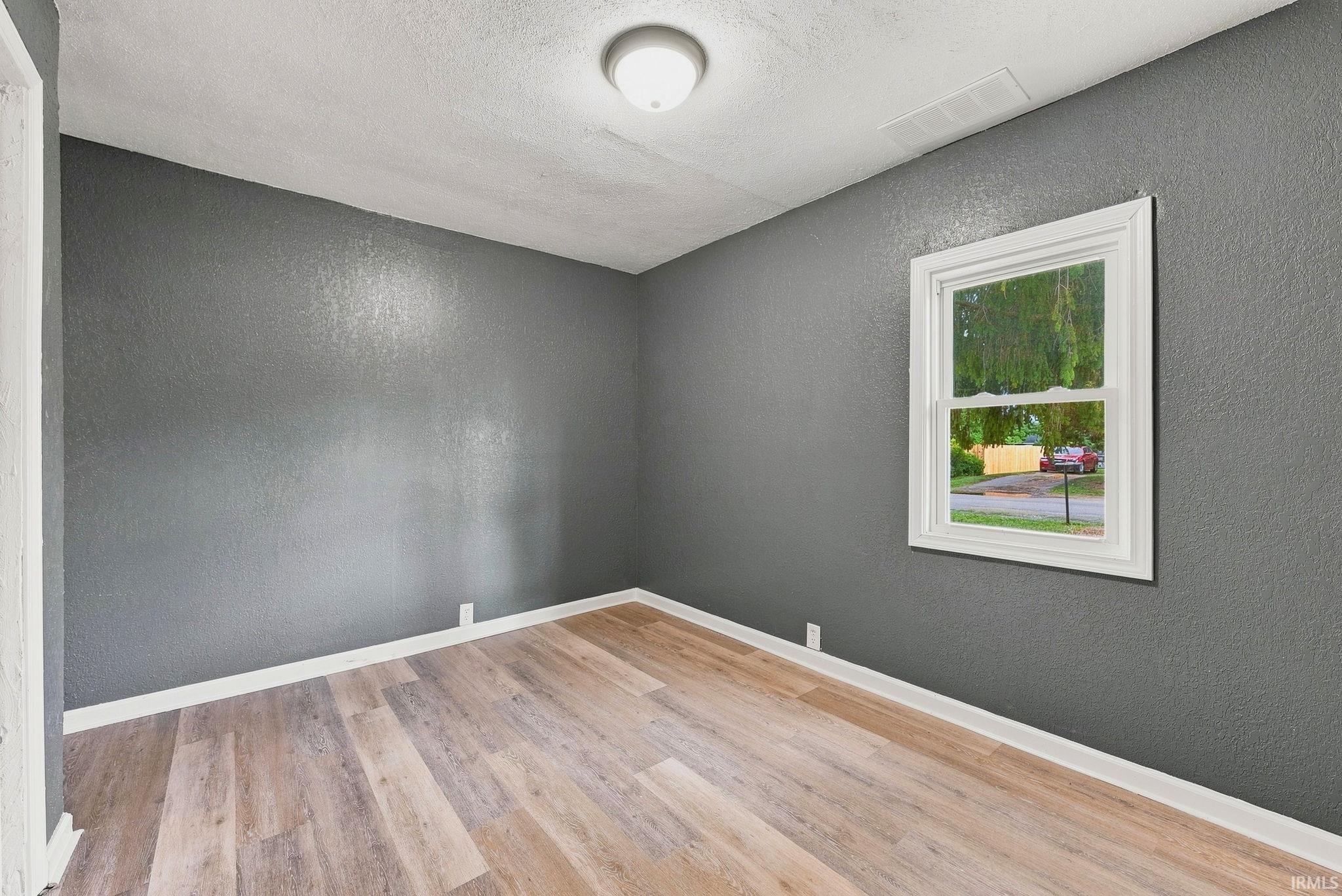 Interior room featuring wood-finish flooring and a single sash window with white trim