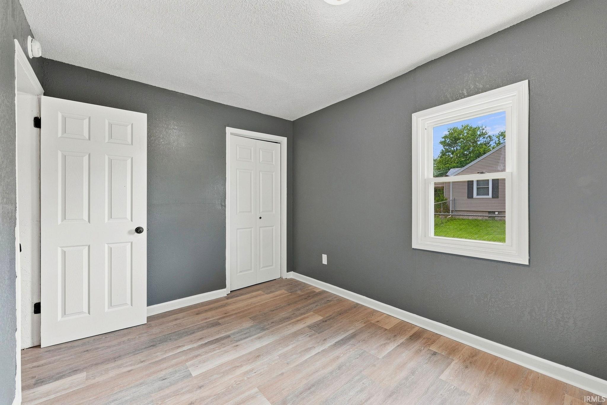 Room featuring light wood-finish flooring, dark gray walls, and white trim