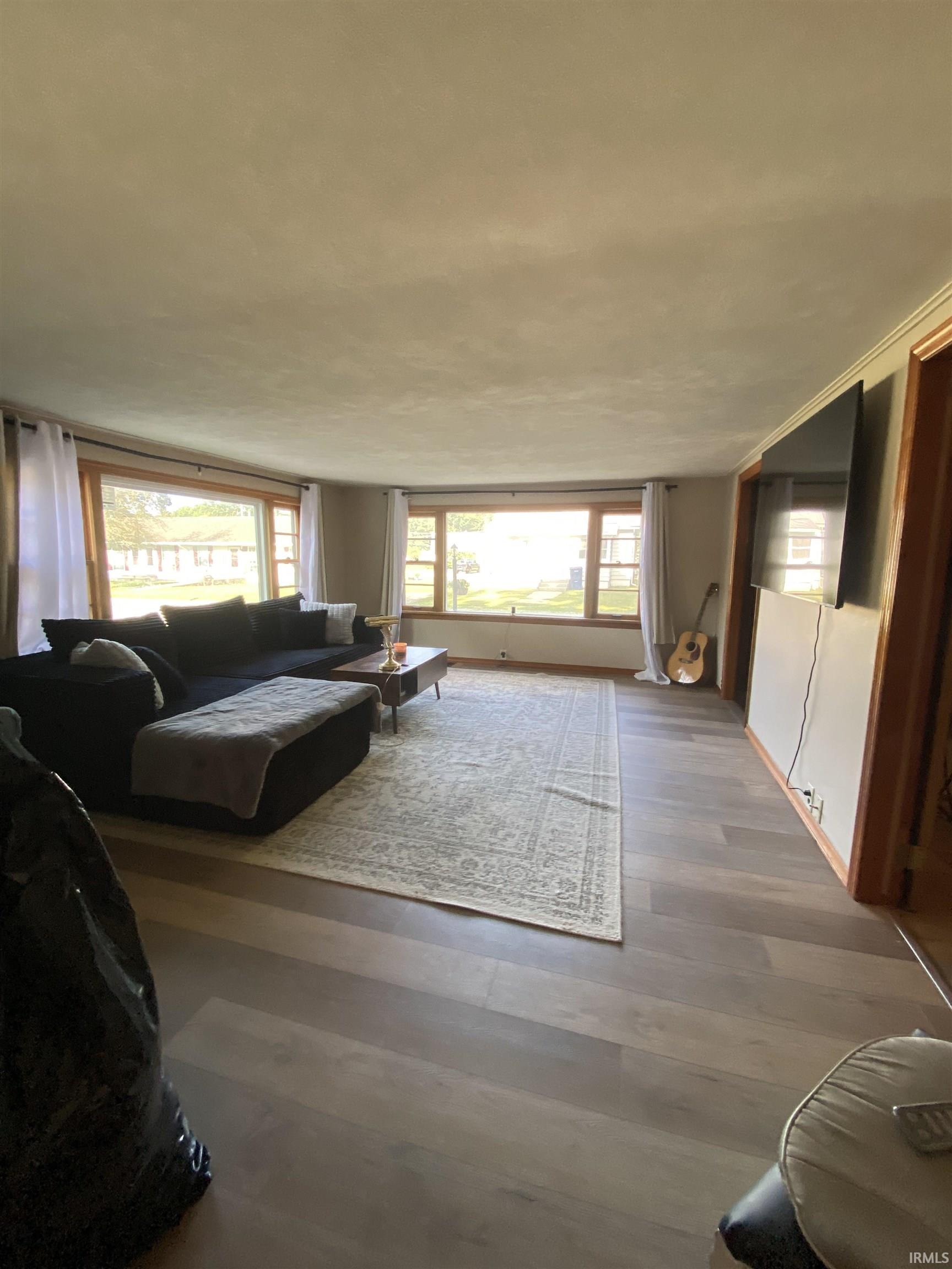 Spacious room featuring wood-finish flooring, multiple large windows, light-toned walls, and wood trim accents