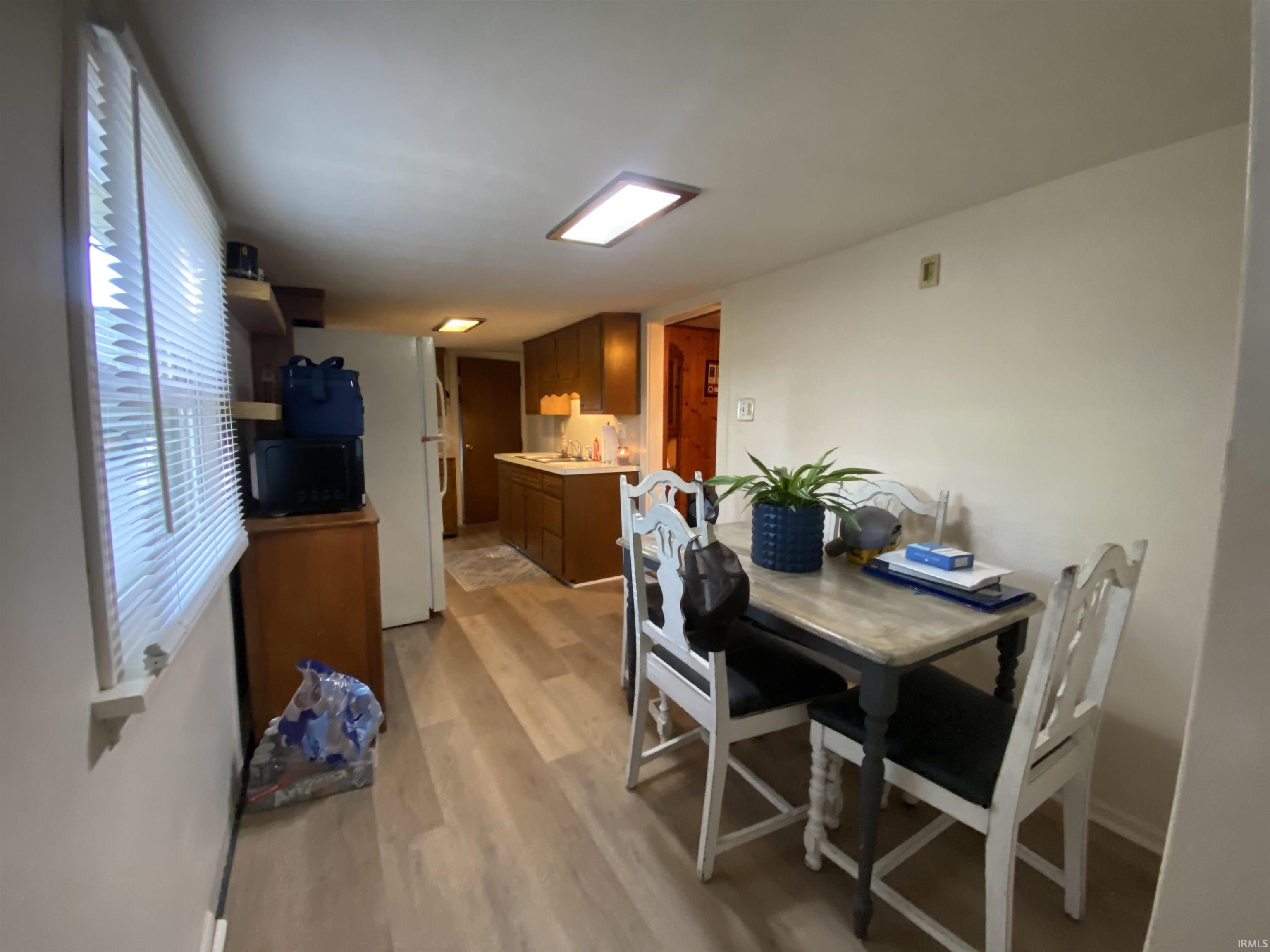 Kitchen dining area featuring wood-finish flooring and a window with blinds