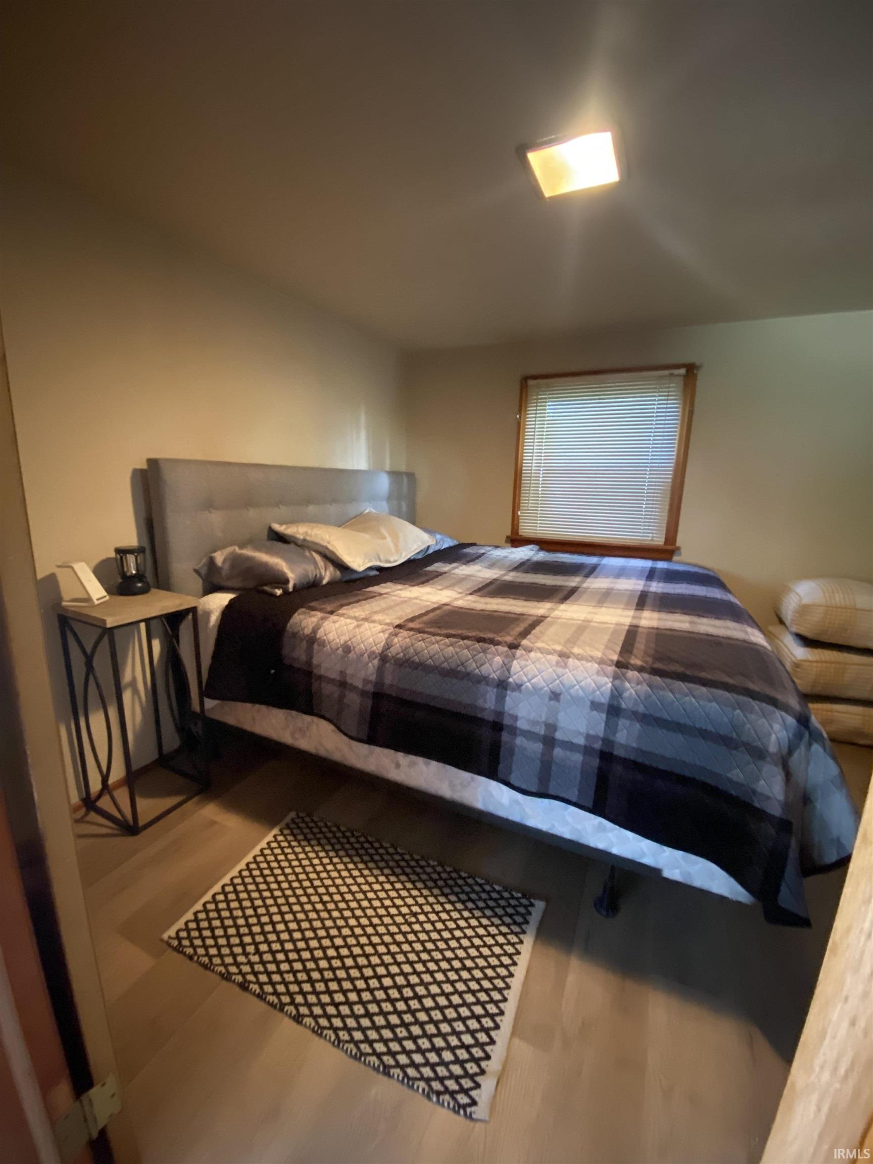 Bedroom featuring light wood-finish flooring and a single window with blinds