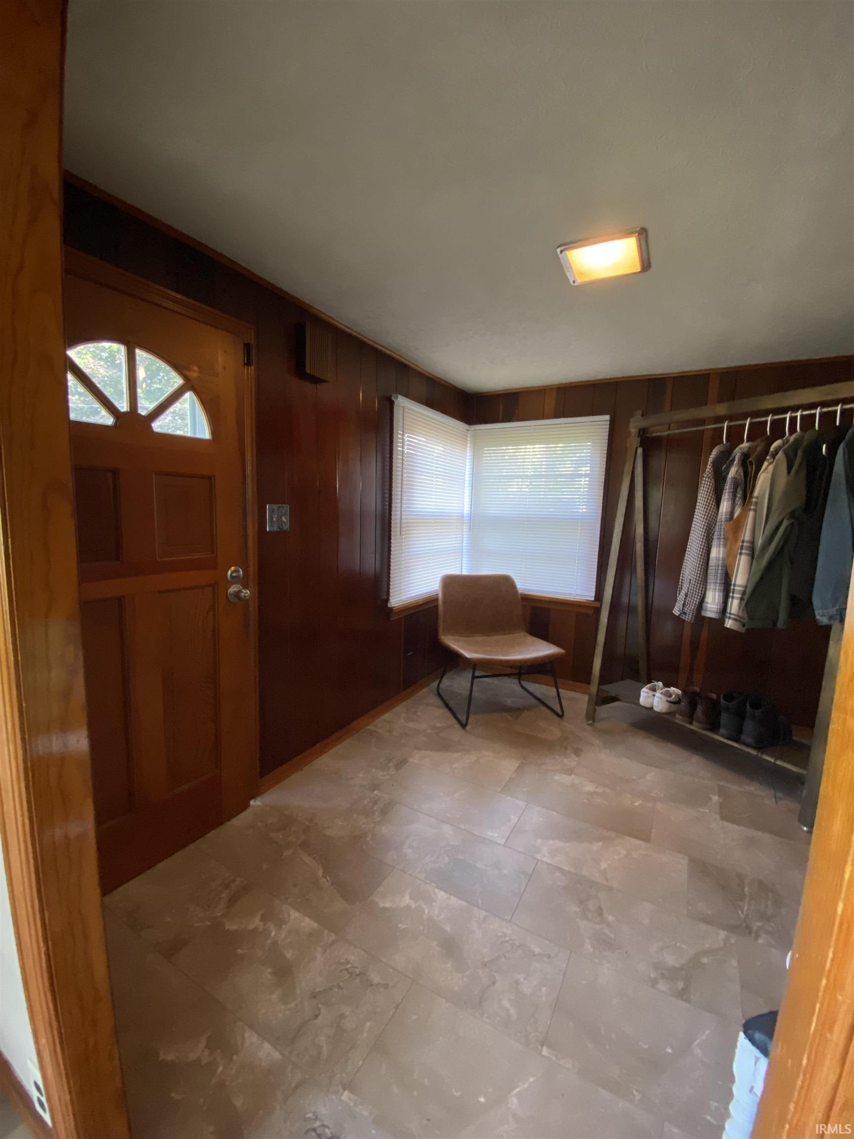 Entryway featuring wood paneling, tiled flooring, and a transom window above the entry door