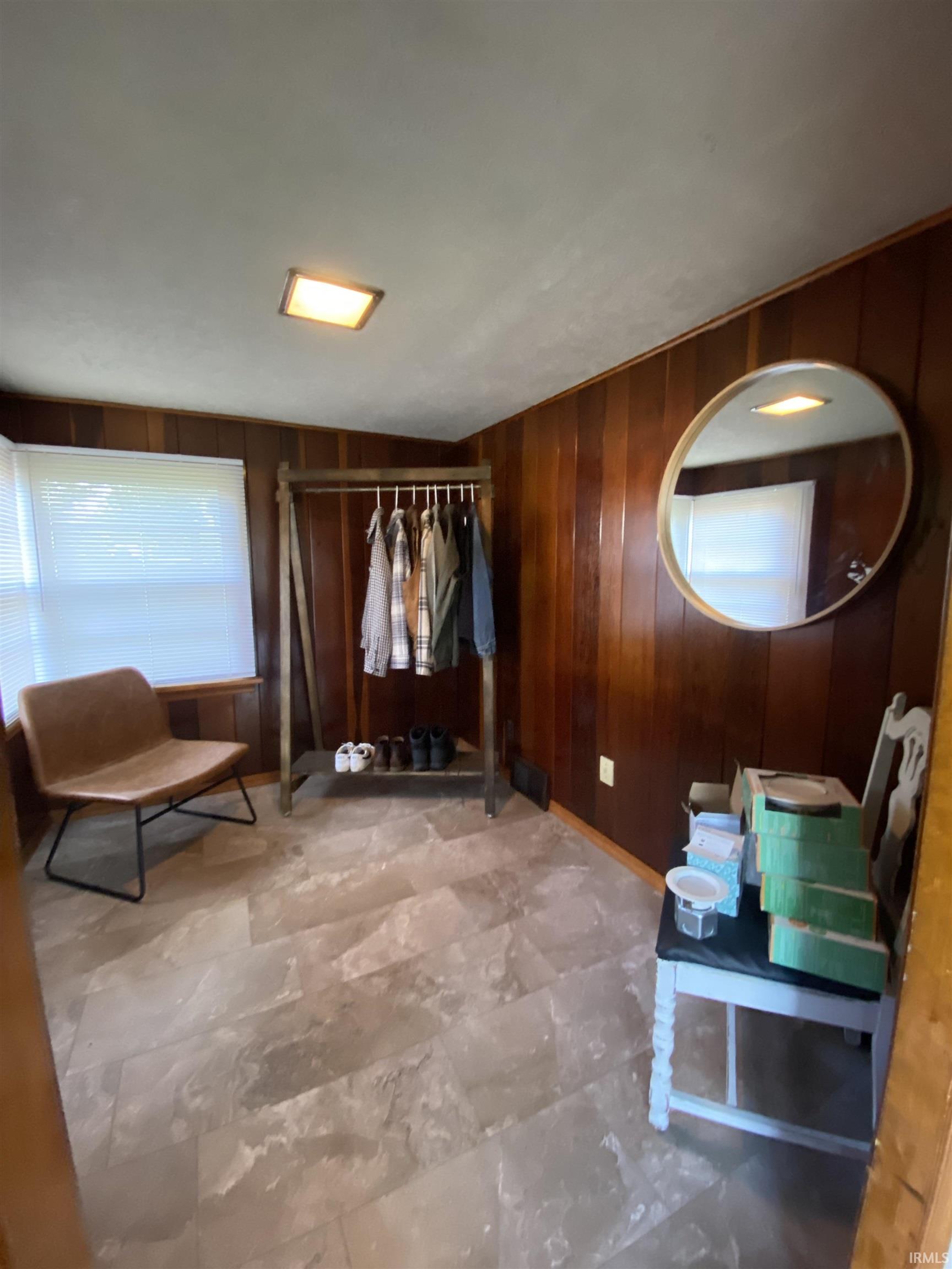 Wood paneling walls frame a room with large windows, light gray ceiling, and slate-style flooring