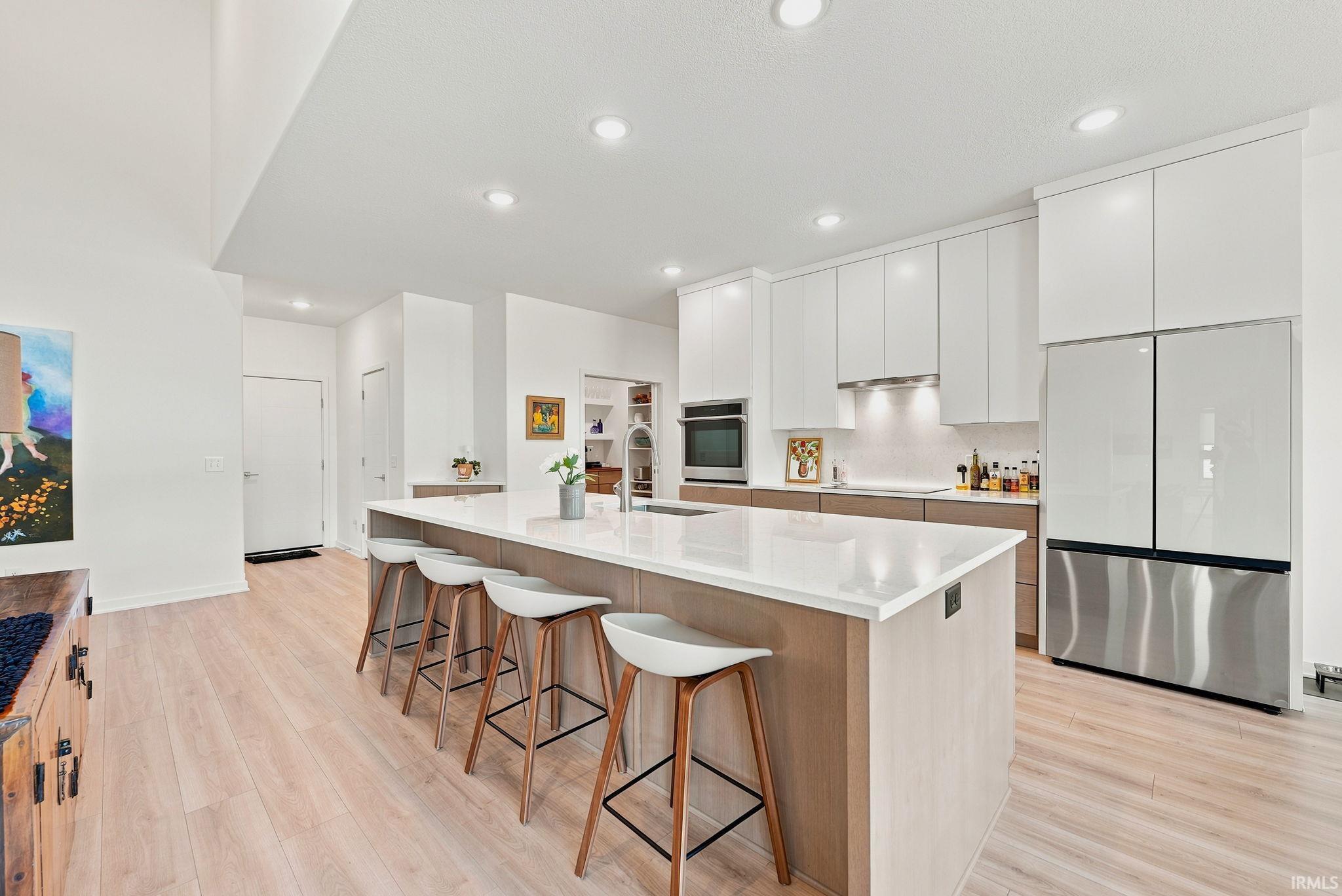 Open-concept kitchen featuring a large island with seating, integrated sink, and white countertop