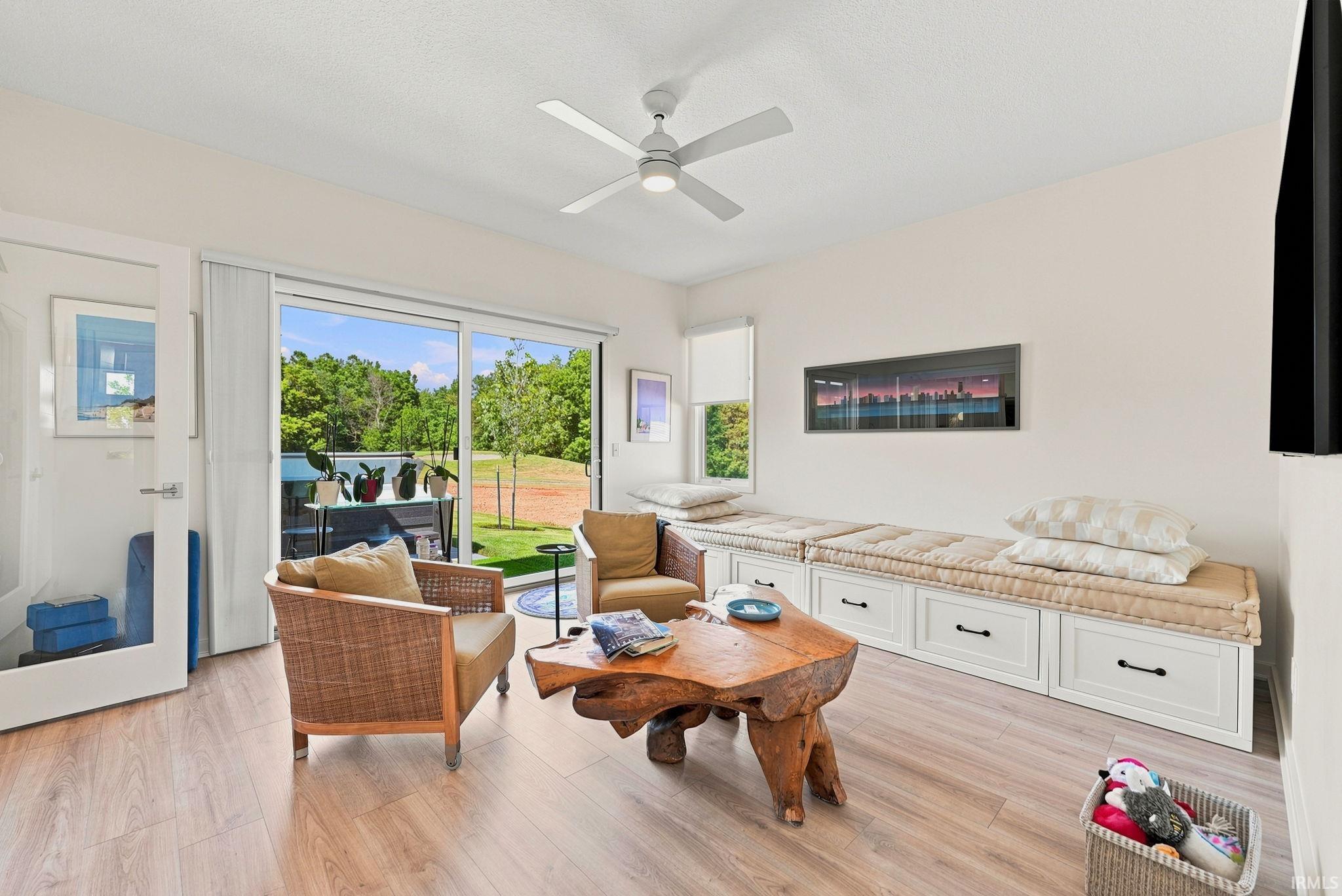 Spacious living area featuring wood-finish flooring, a ceiling fan, and extensive built-in bench seating with integrated storage drawers