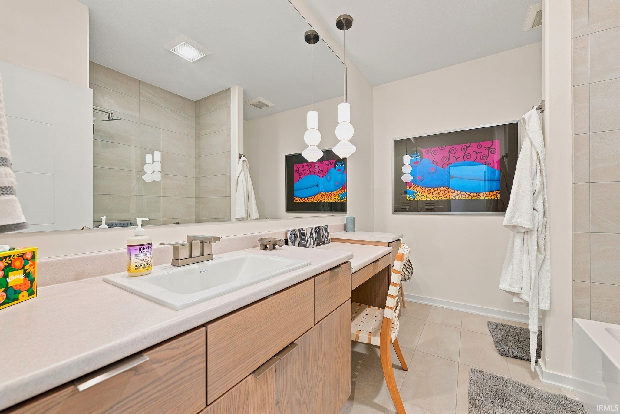 Bathroom featuring an elongated vanity with an integrated sink, brushed nickel faucet, and light wood-finish cabinetry