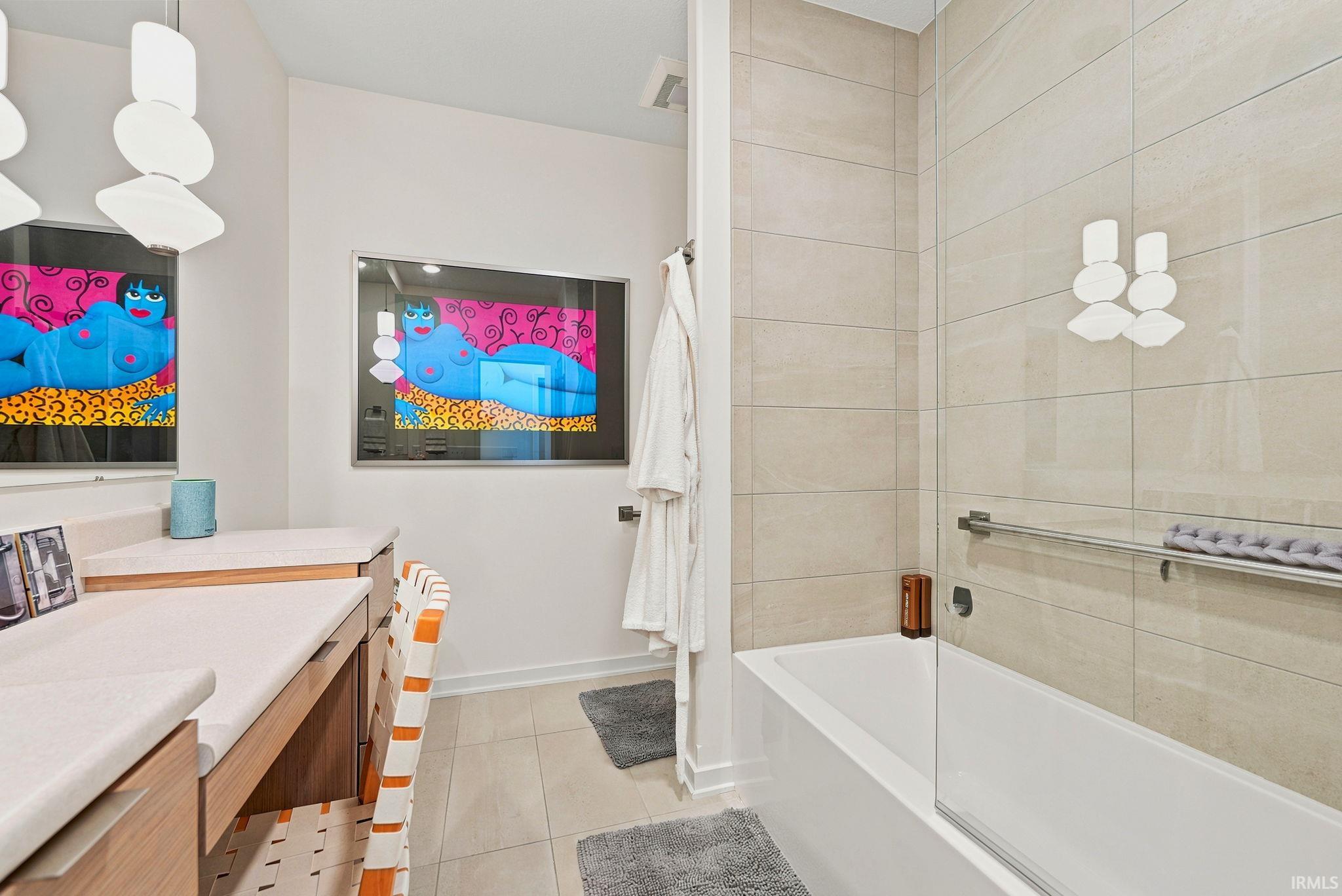 Bathroom featuring a built-in bathtub with a clear glass shower panel and light-toned tile surround