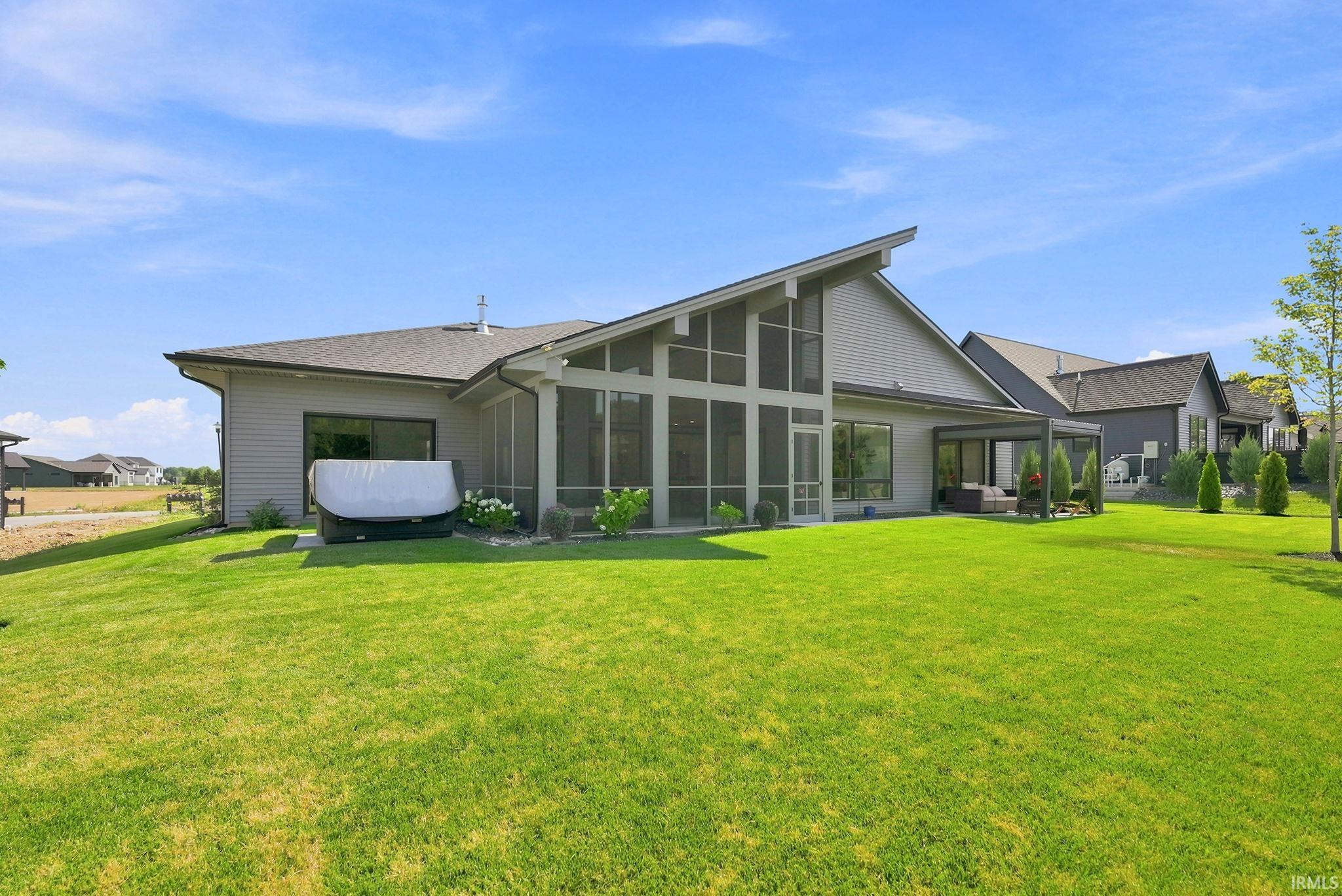 Spacious rear exterior featuring a screened porch, covered patio, and large lawn area