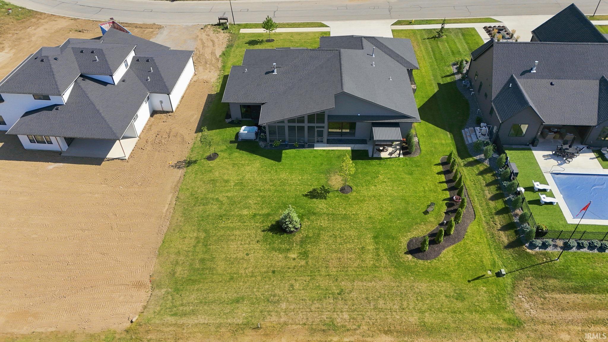Spacious rear yard featuring manicured lawn, established landscaping, and a covered patio