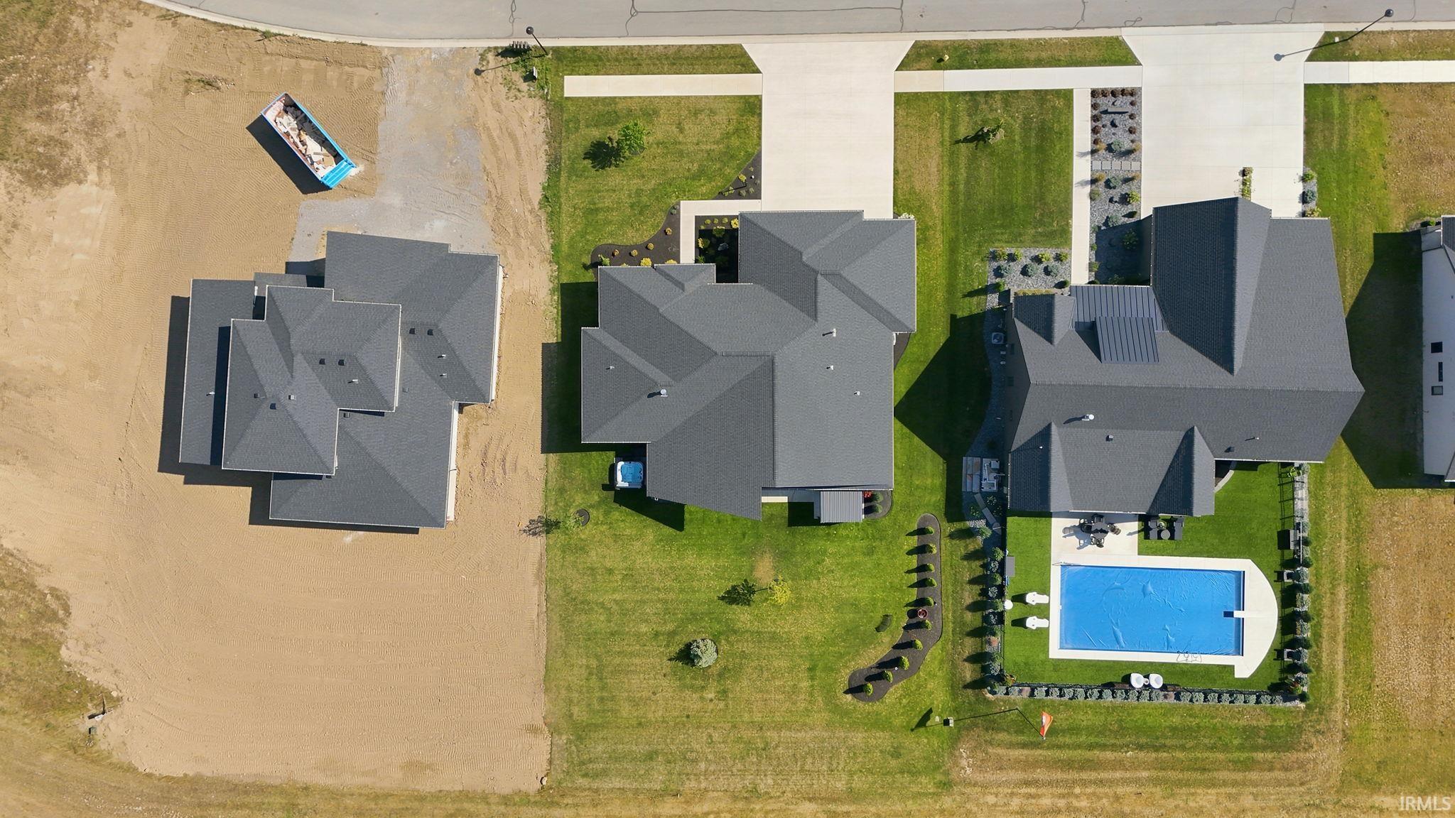 Expansive property featuring a rectangular pool with a cover, surrounded by a manicured lawn and mature landscaping