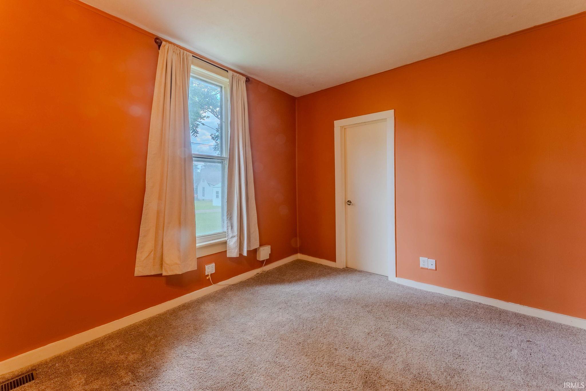 Interior room featuring orange walls and light-colored carpeting
