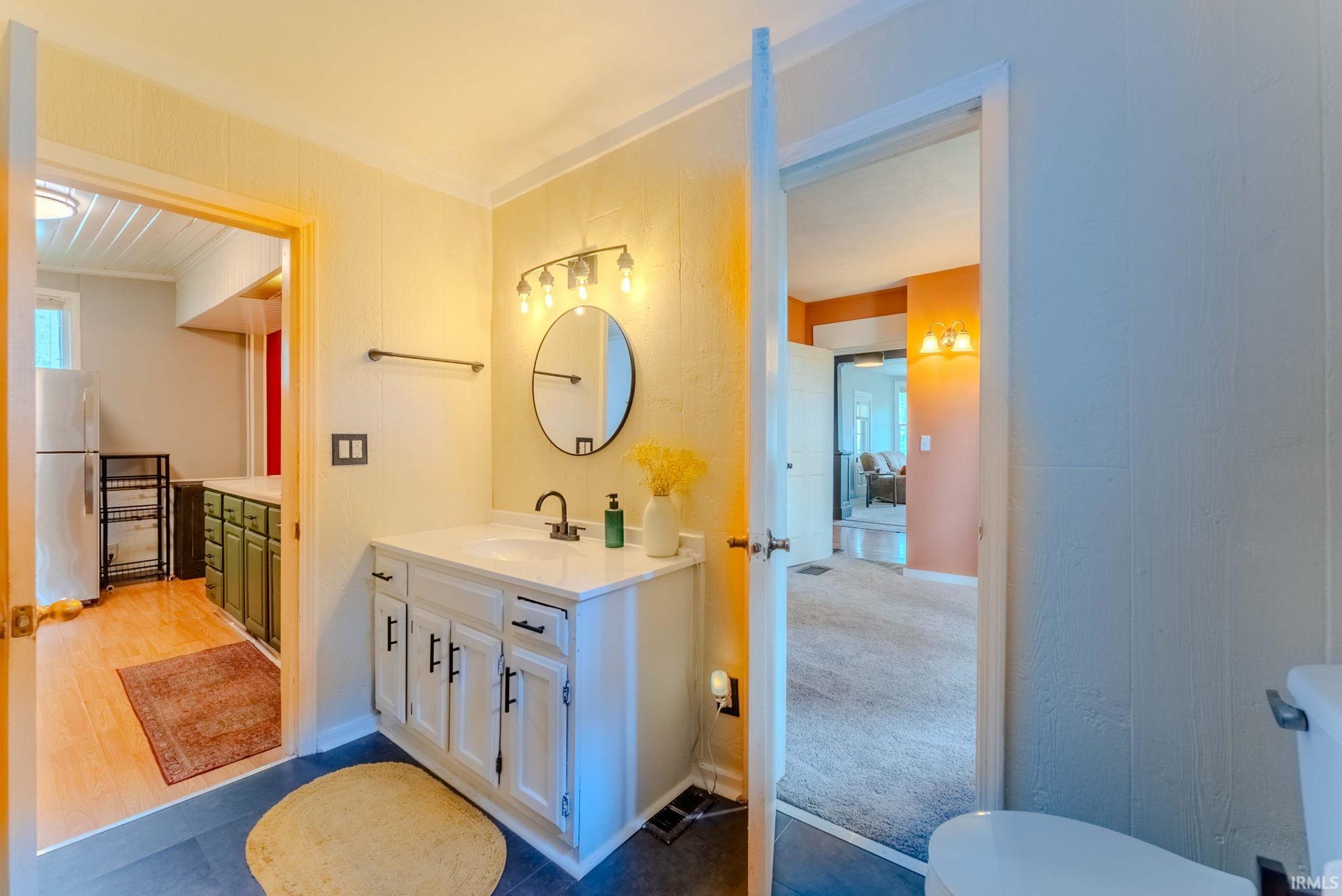 Vanity with white cabinetry, black hardware, and a single-basin sink under a circular mirror