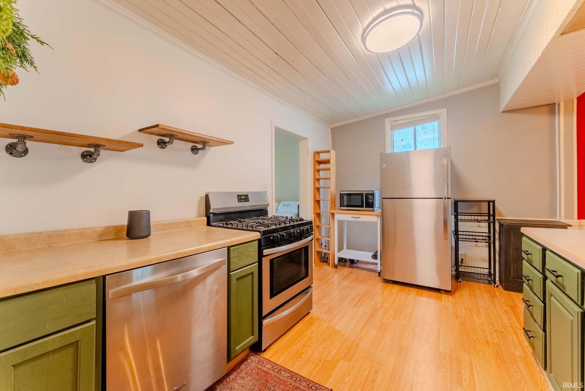 Kitchen featuring stainless steel appliances, wood-finish flooring, and painted cabinetry