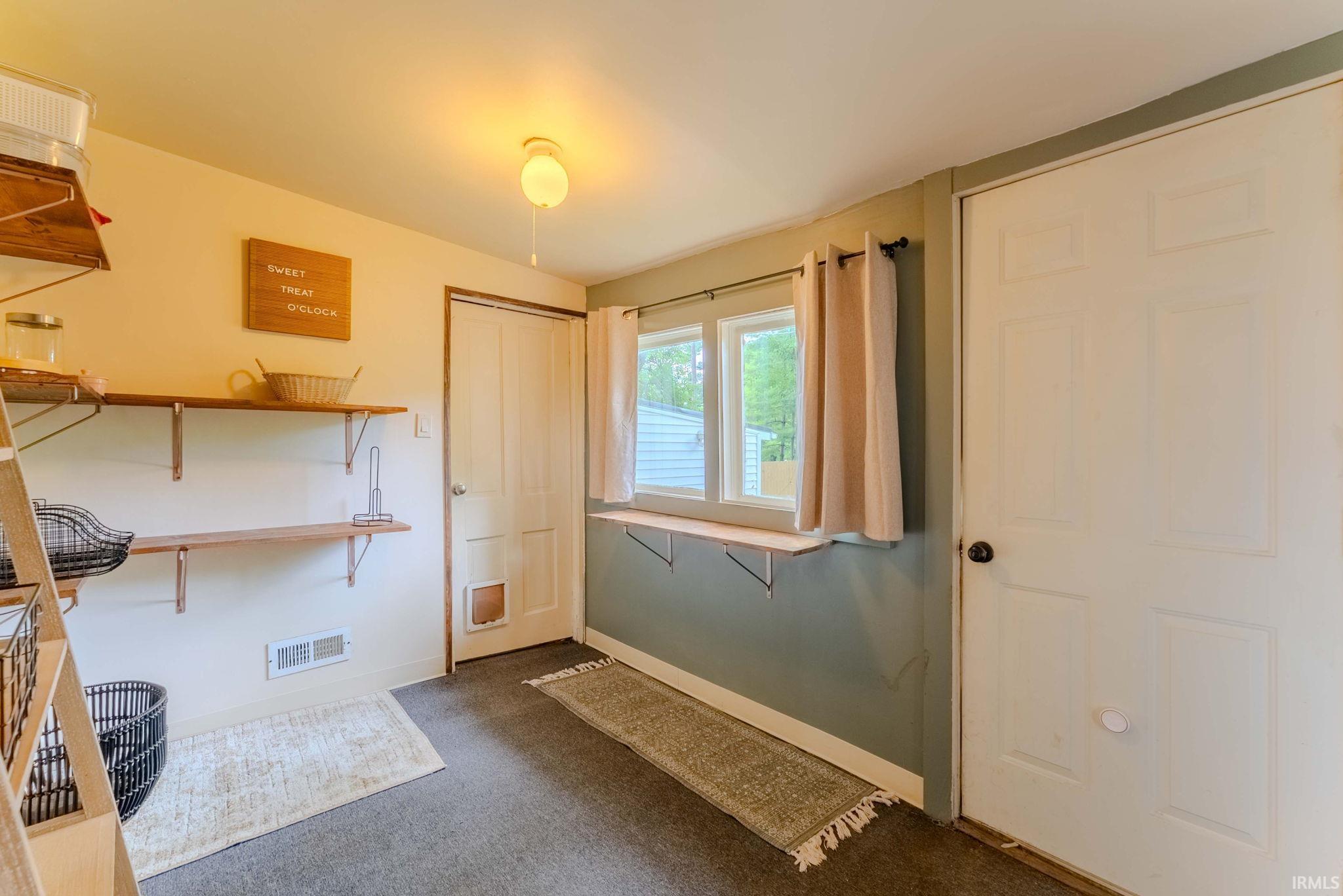 Functional utility room featuring multiple wood shelves, two white panel doors, and a window with a sill