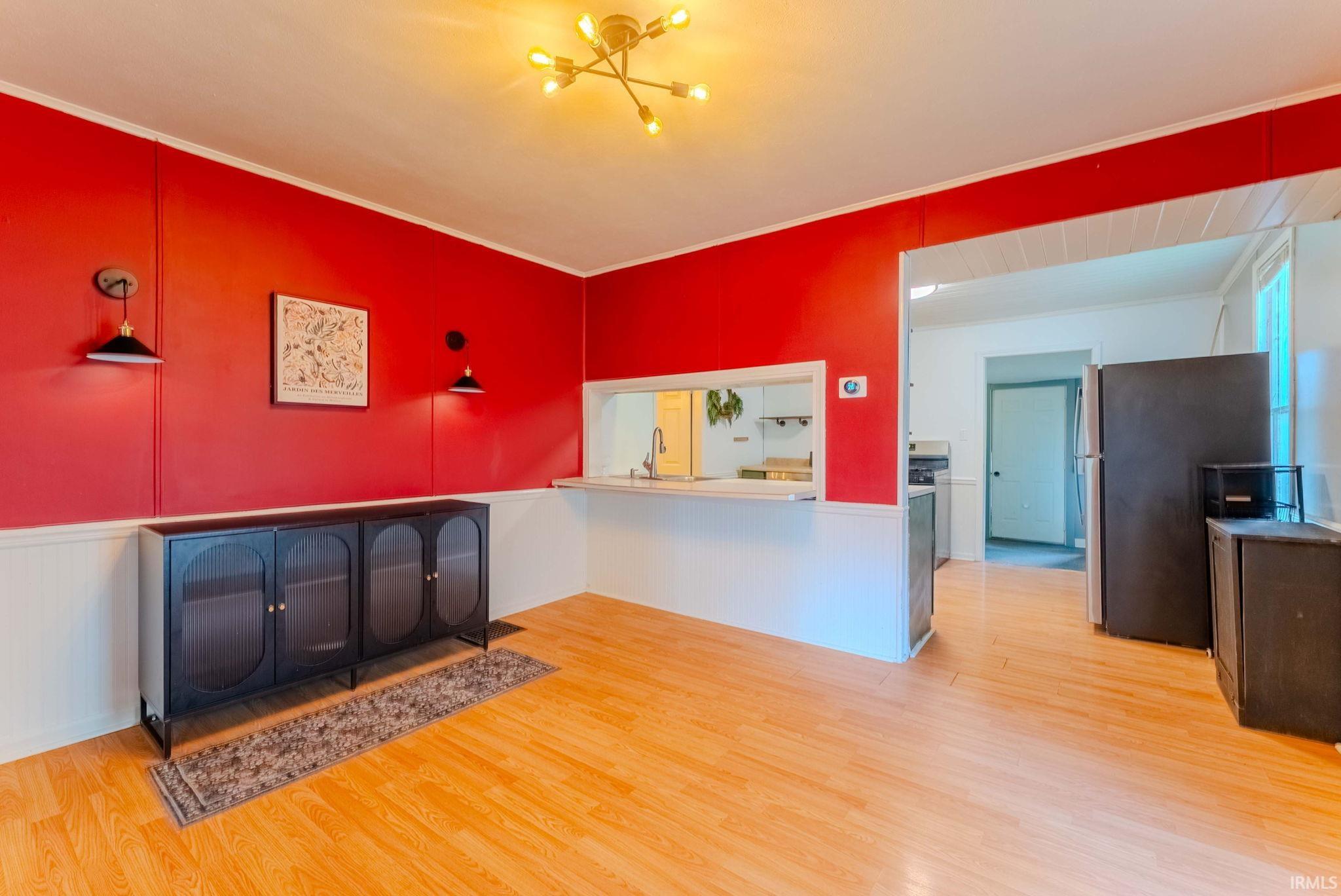 Open-concept room featuring light wood-finish flooring and a pass-through window to the kitchen