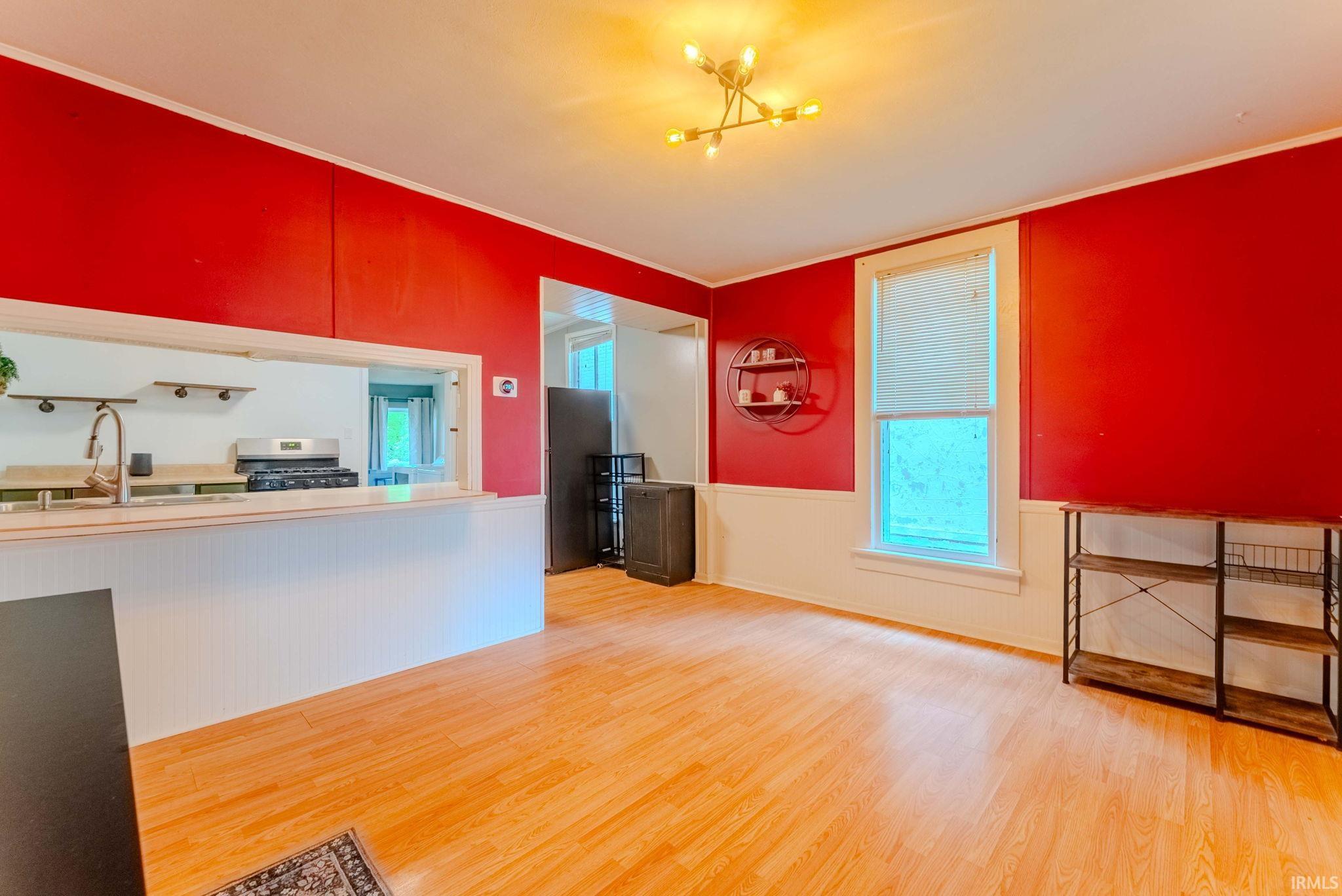 Open-concept living area featuring wood-finish flooring, a pass-through window to the kitchen, and a ceiling-mounted light fixture