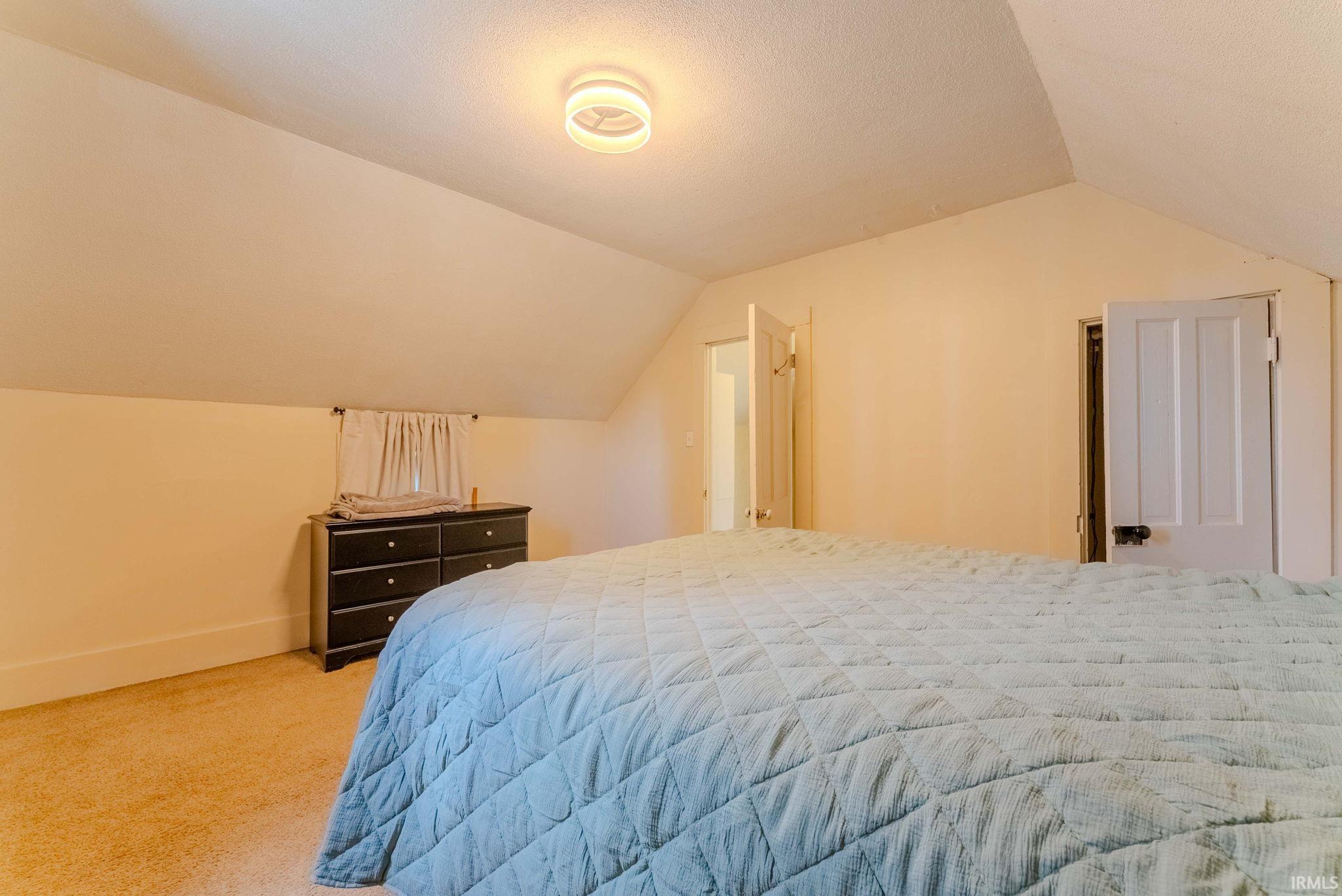 Carpeted room featuring a sloped ceiling and flush-mount lighting