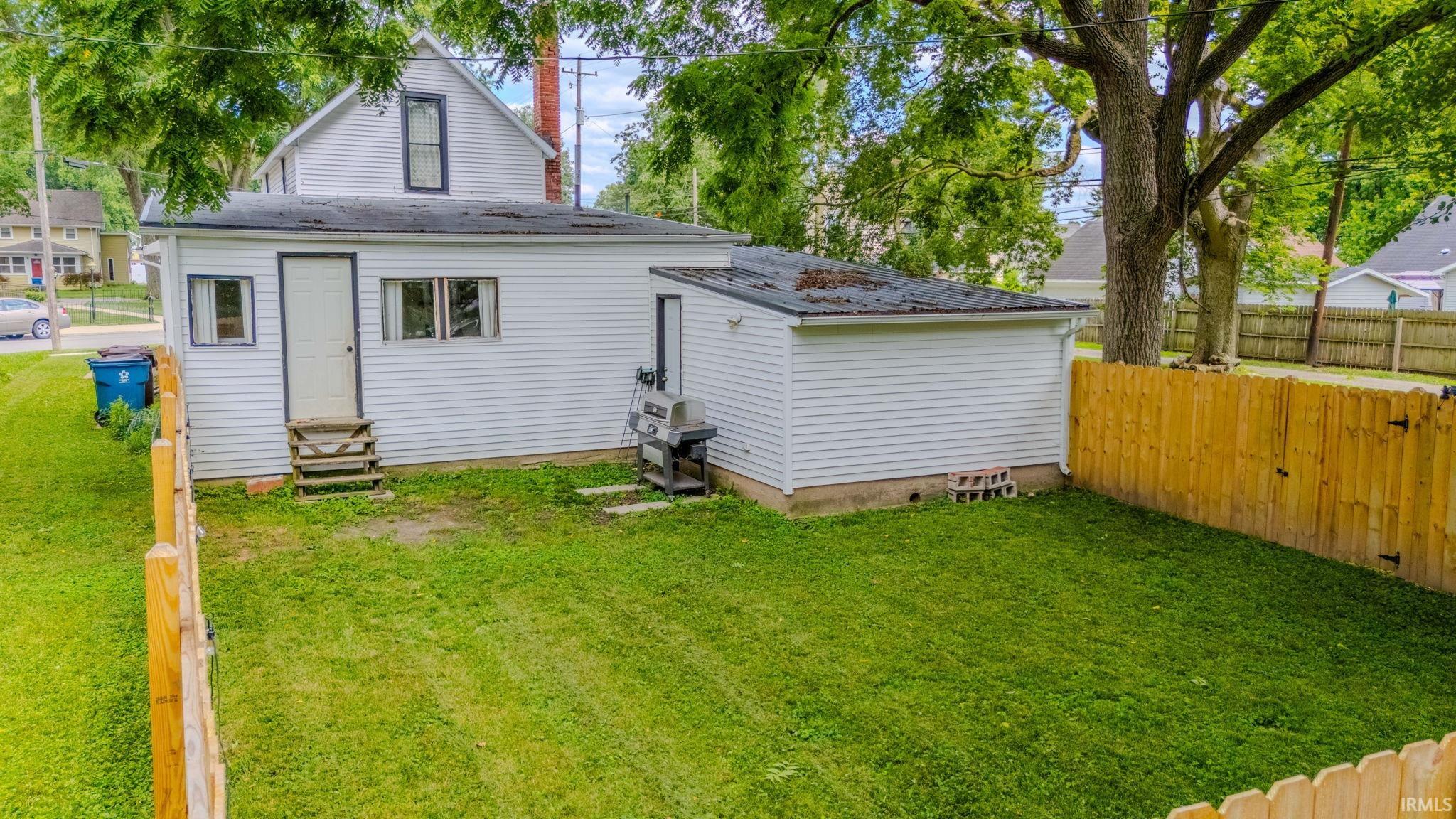 Expansive backyard featuring a manicured lawn, a complete wood privacy fence, and mature trees providing natural shade