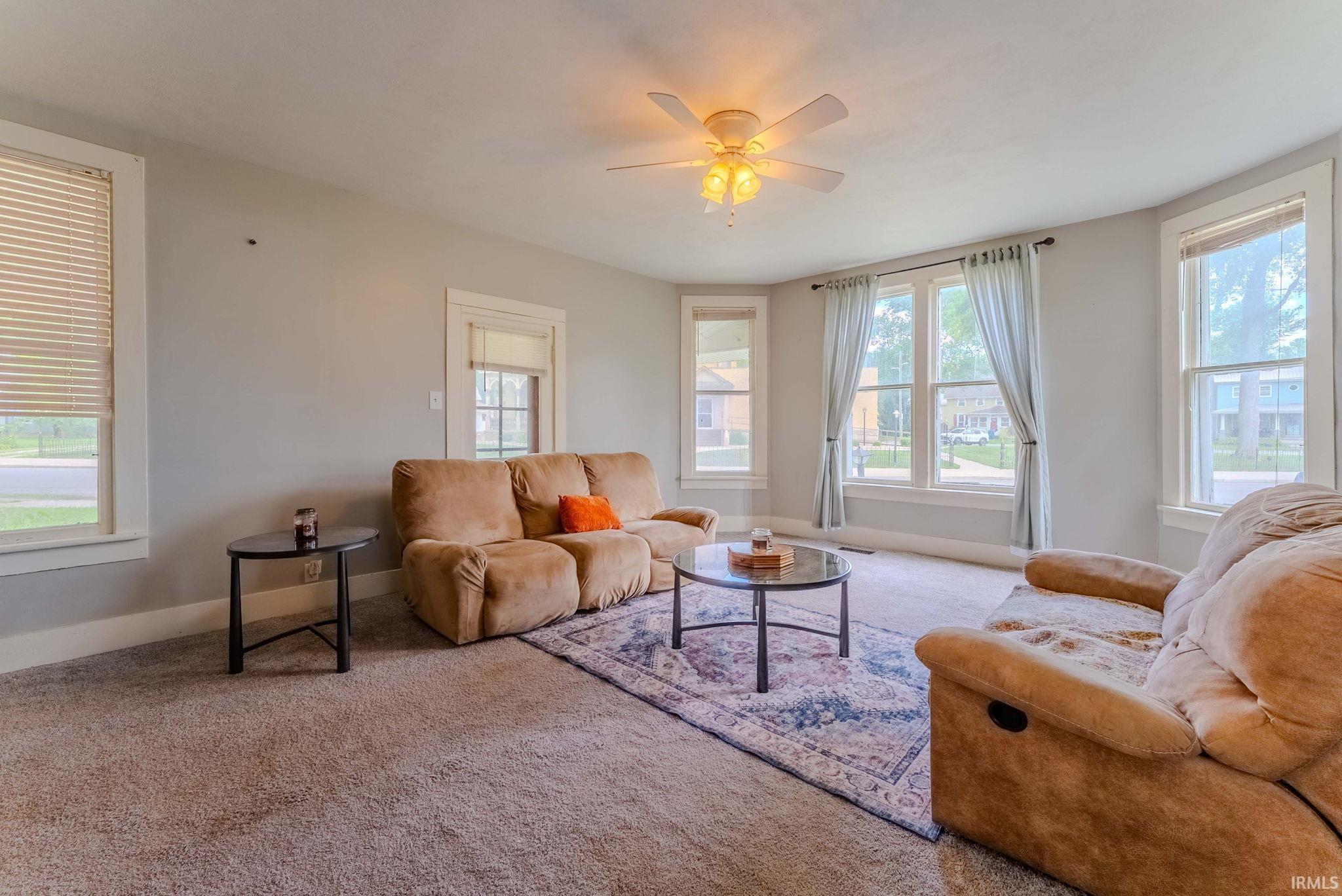 Spacious living area featuring light gray walls and plush carpeting