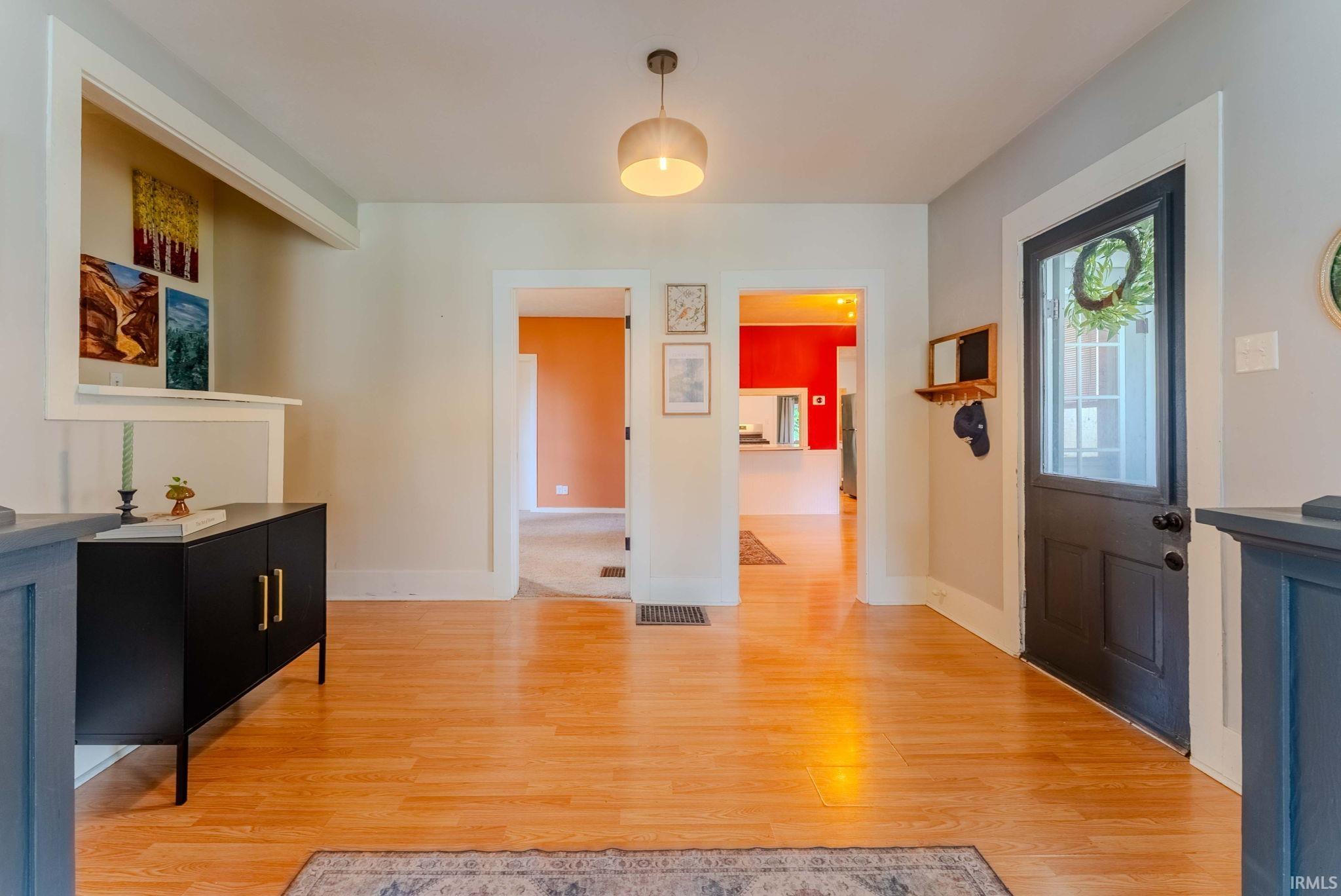 Bright interior with wood-finish flooring, a contemporary ceiling light fixture, and white baseboards