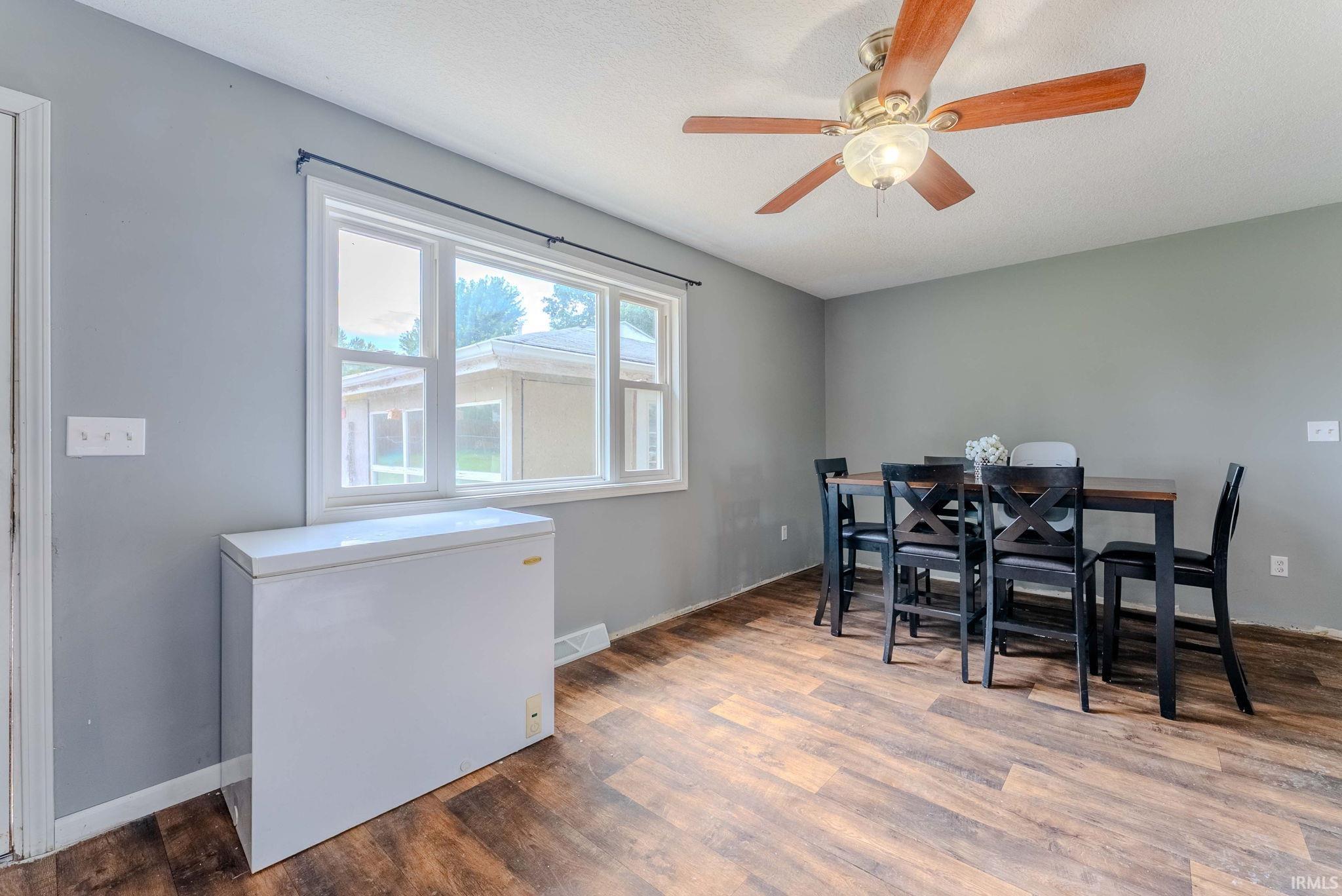 Windowed room featuring wood-finish flooring, a ceiling fan with integrated lighting, and neutral wall tones