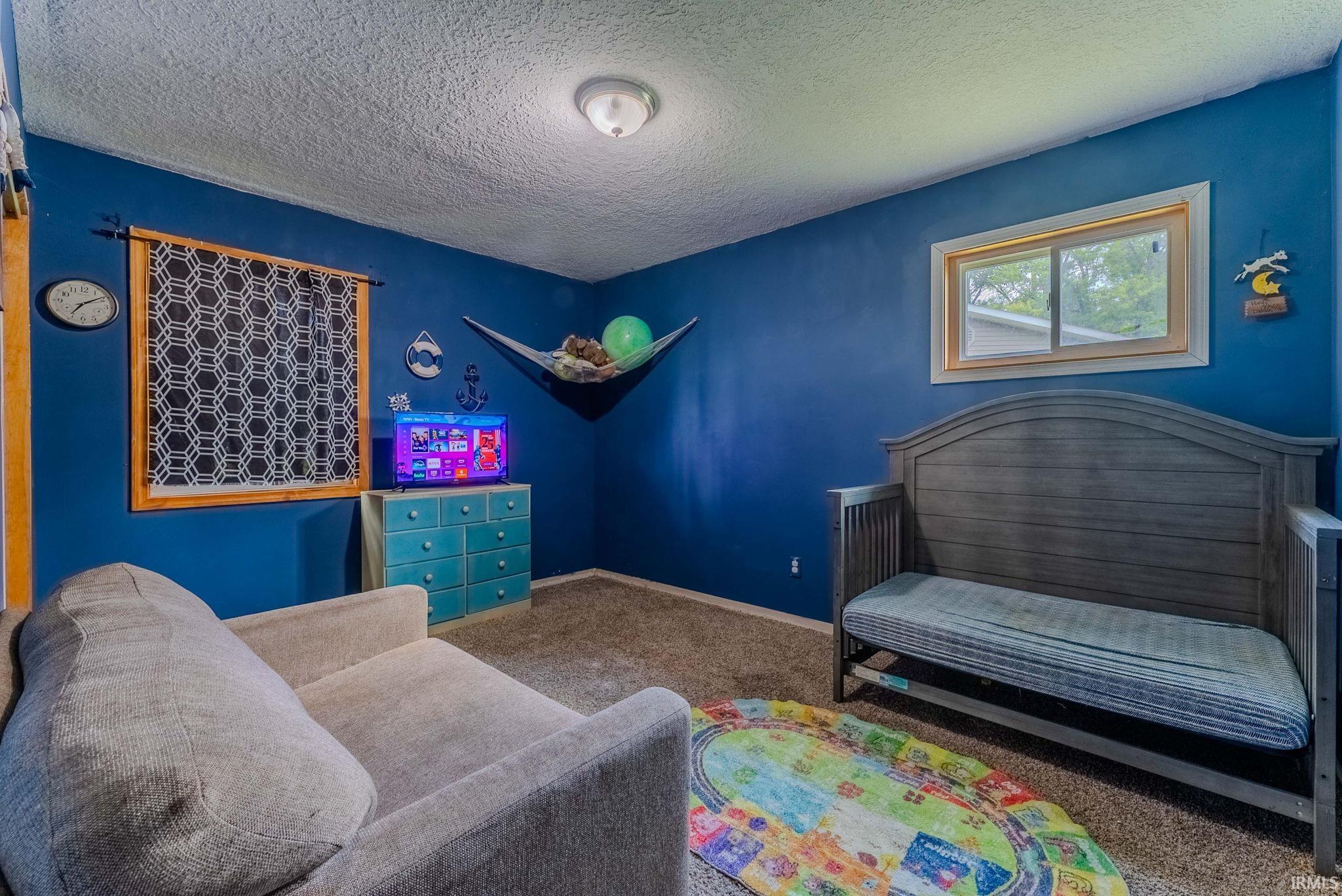 Interior room featuring blue wall paint, textured ceiling, and two windows with wood-finish trim