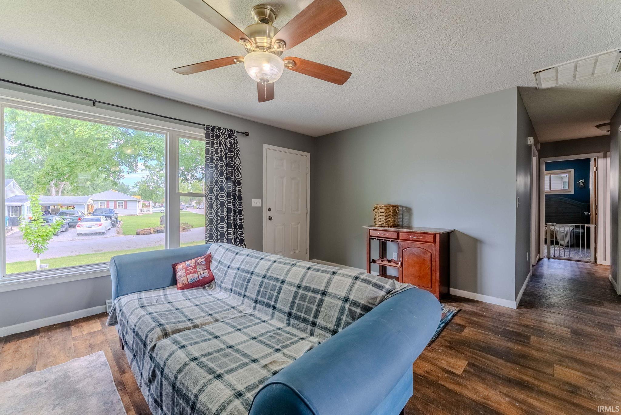 Spacious interior with wood-finish flooring, a contemporary ceiling fan, and a large picture window