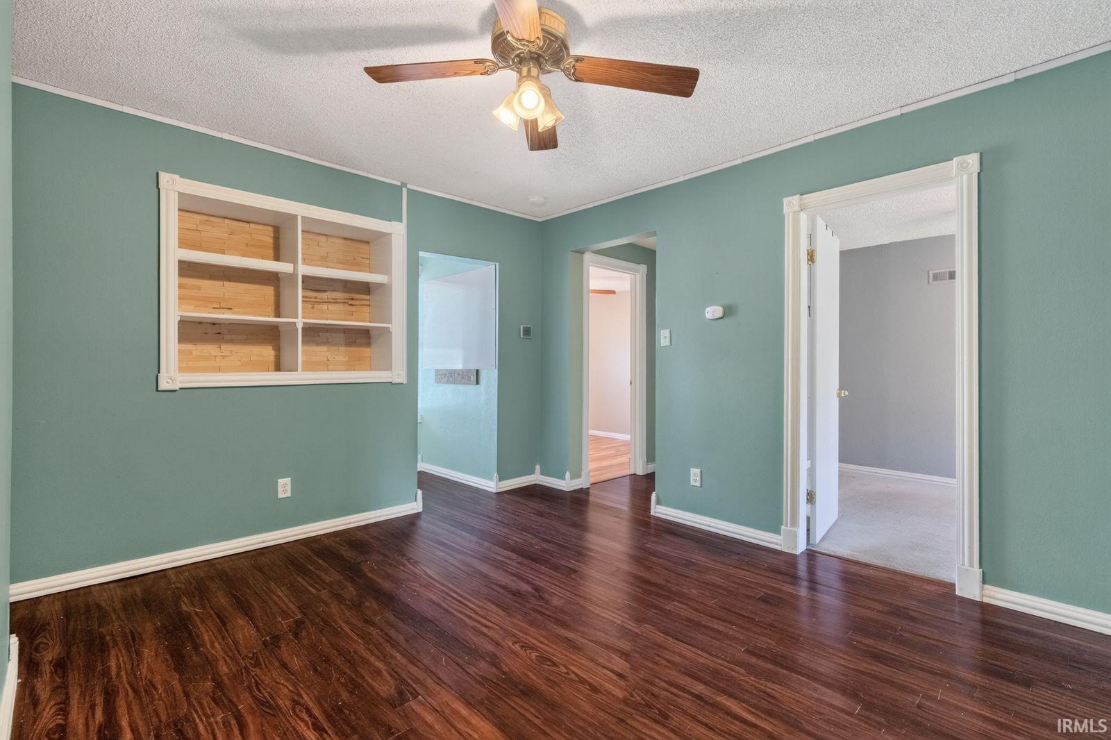 Spacious room featuring wood-finish flooring, light teal walls, and white baseboards